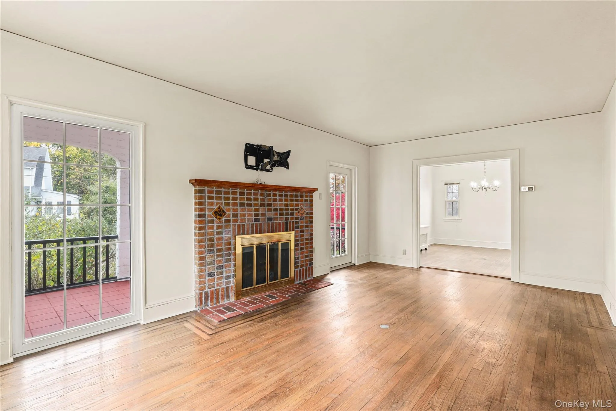 Unfurnished living room with hardwood / wood-style floors, a tiled fireplace, and a chandelier Unfurnished living room with hardwood / wood-style floors, a tiled fireplace, and a chandelier