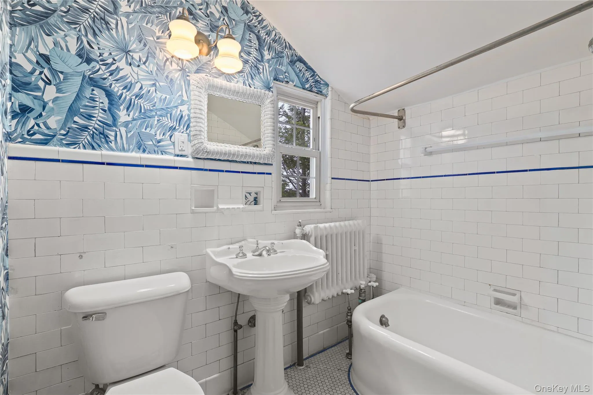 Bathroom featuring radiator heating unit, tile walls, shower / bath combination with curtain, vaulted ceiling, and wallpapered walls Bathroom featuring radiator heating unit, tile walls, shower / bath combination with curtain, vaulted ceiling, and wallpapered walls