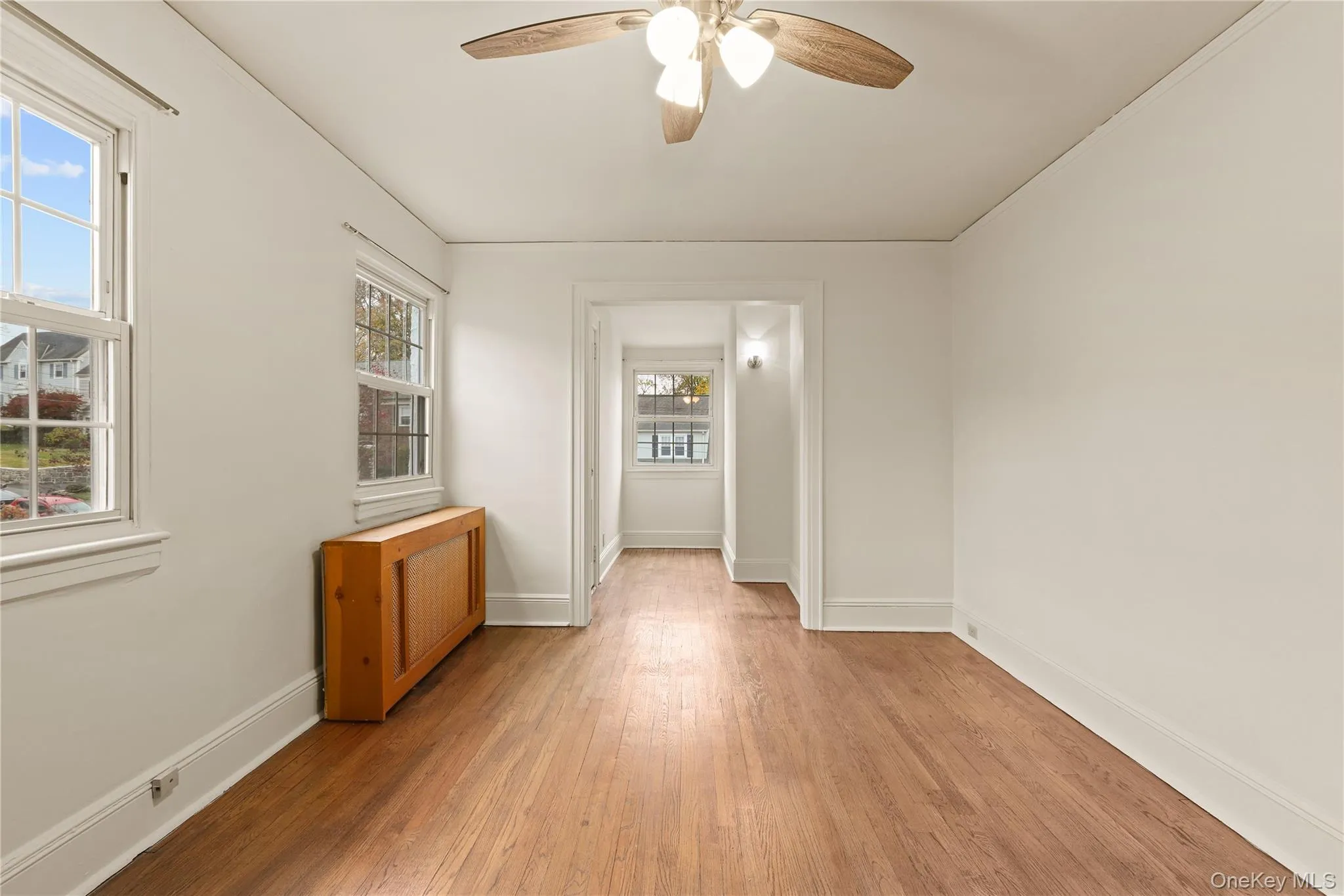 Spare room with wood finished floors, radiator, and a ceiling fan Spare room with wood finished floors, radiator, and a ceiling fan
