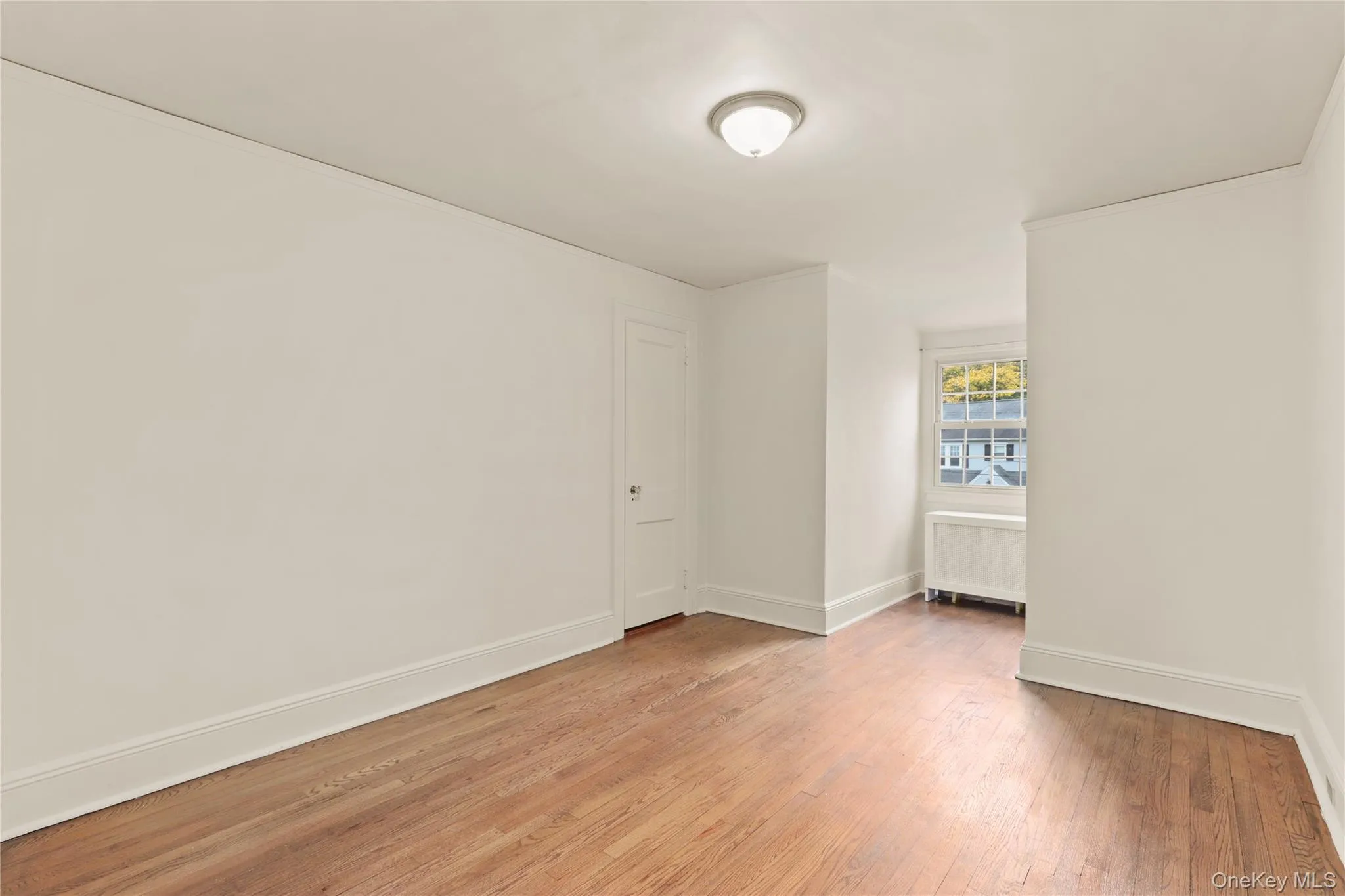 Spare room with light wood-type flooring, radiator heating unit, and crown molding Spare room with light wood-type flooring, radiator heating unit, and crown molding