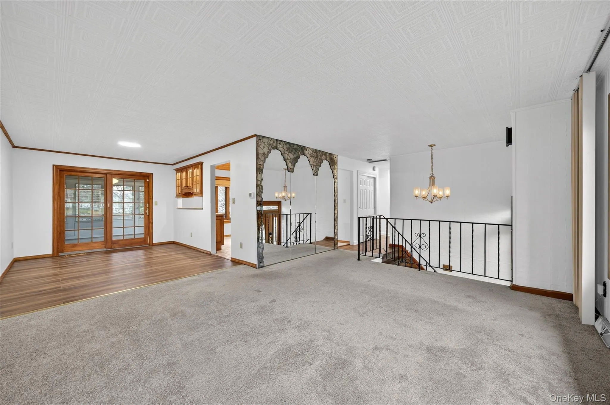 Unfurnished living room featuring a chandelier, carpet flooring, wood finished floors, and crown molding Unfurnished living room featuring a chandelier, carpet flooring, wood finished floors, and crown molding