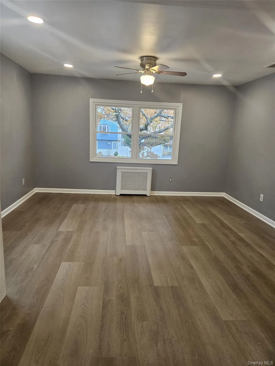 Unfurnished room featuring recessed lighting, wood finished floors, radiator heating unit, and a ceiling fan Unfurnished room featuring recessed lighting, wood finished floors, radiator heating unit, and a ceiling fan