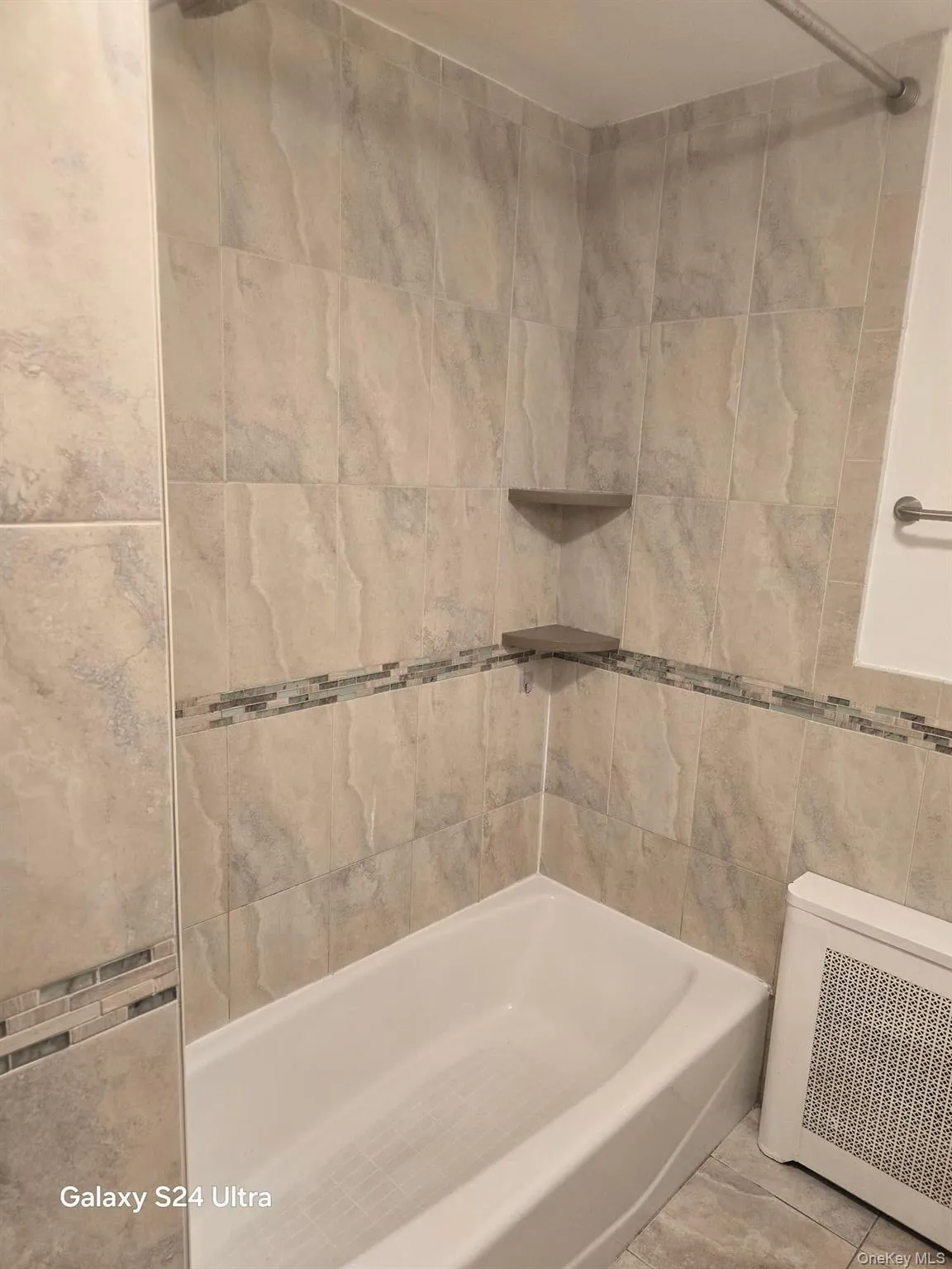 Bathroom featuring radiator, tile walls, and bathtub / shower combination Bathroom featuring radiator, tile walls, and bathtub / shower combination