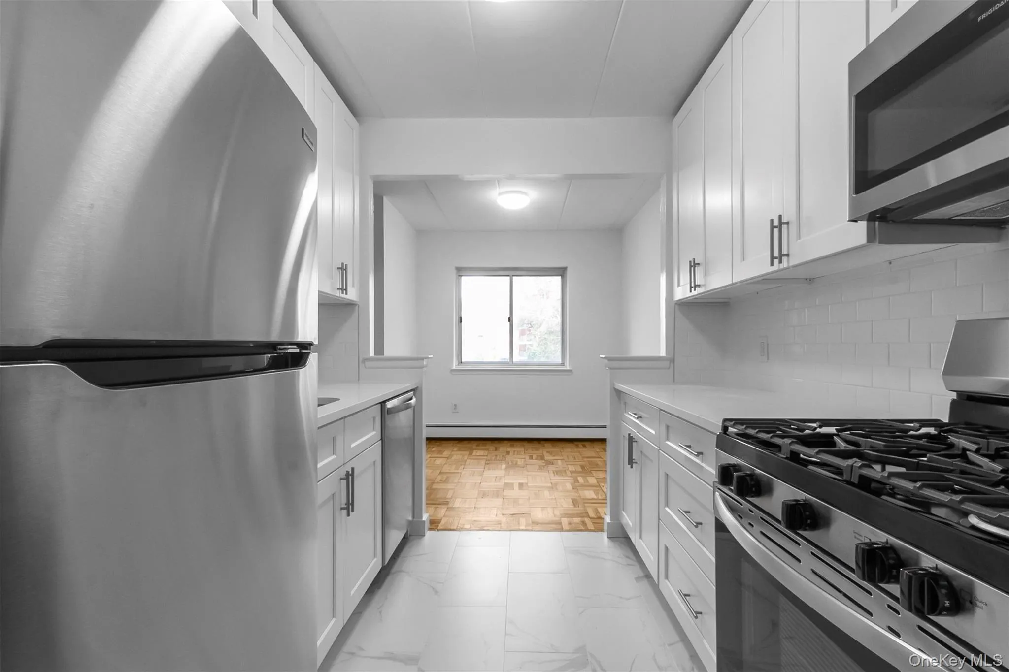 Kitchen featuring stainless steel appliances, white cabinetry, and light stone counters Kitchen featuring stainless steel appliances, white cabinetry, and light stone counters