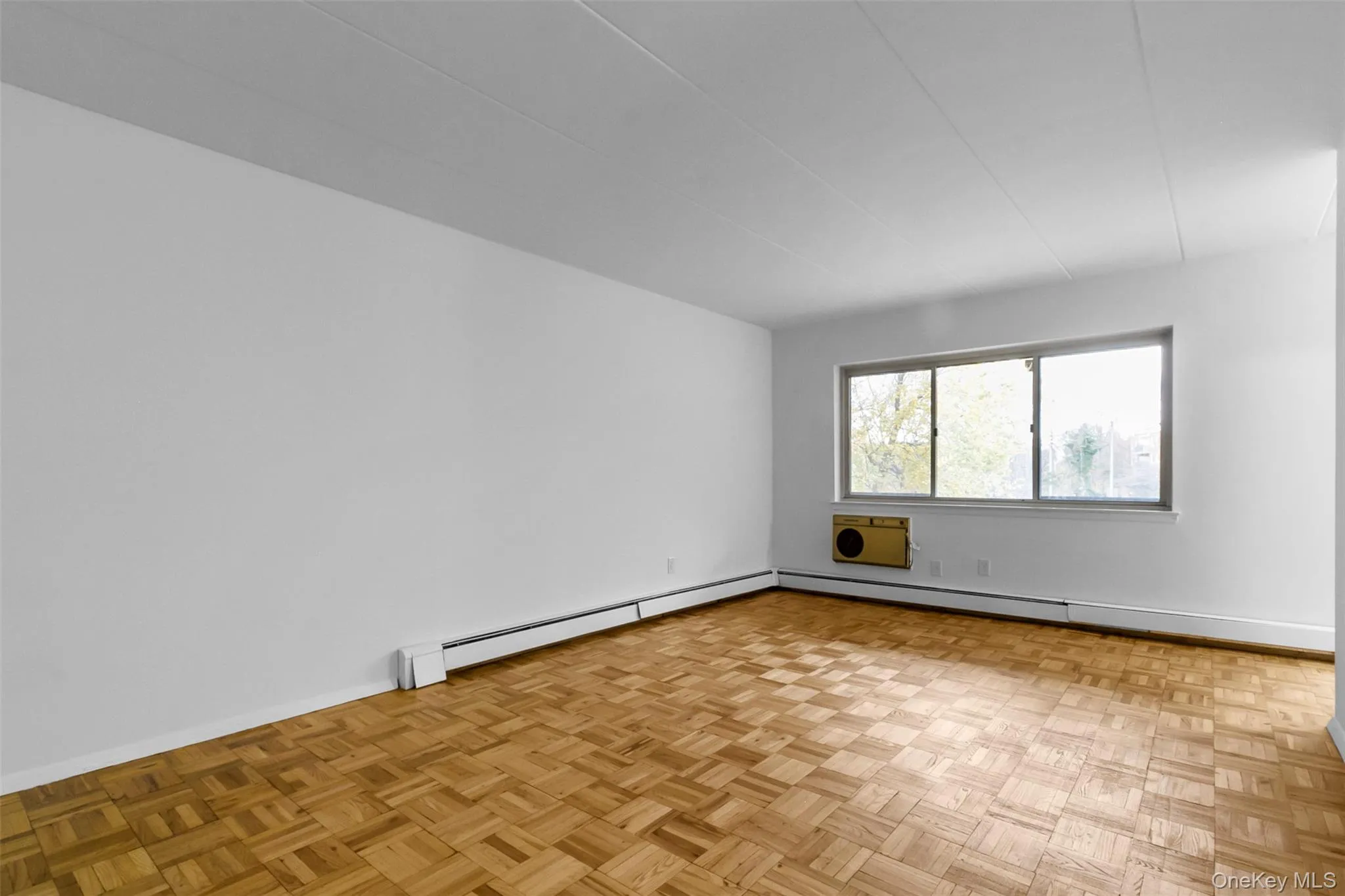 Unfurnished room with a baseboard heating unit and a wall mounted AC Unfurnished room with a baseboard heating unit and a wall mounted AC