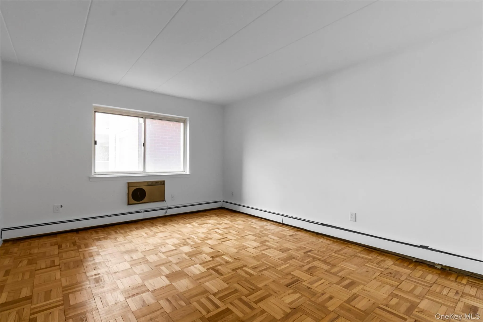 Empty room featuring a baseboard radiator and a wall unit AC Empty room featuring a baseboard radiator and a wall unit AC
