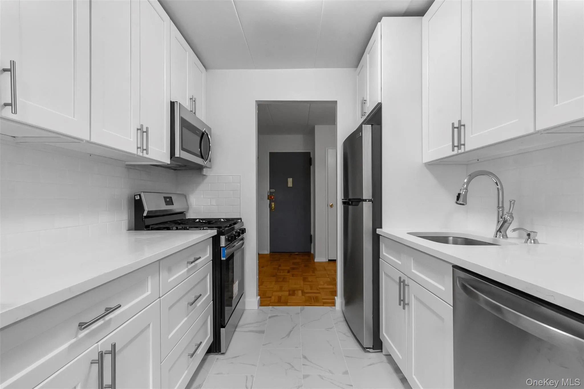 Kitchen featuring stainless steel appliances, backsplash, light stone counters, and white cabinets Kitchen featuring stainless steel appliances, backsplash, light stone counters, and white cabinets
