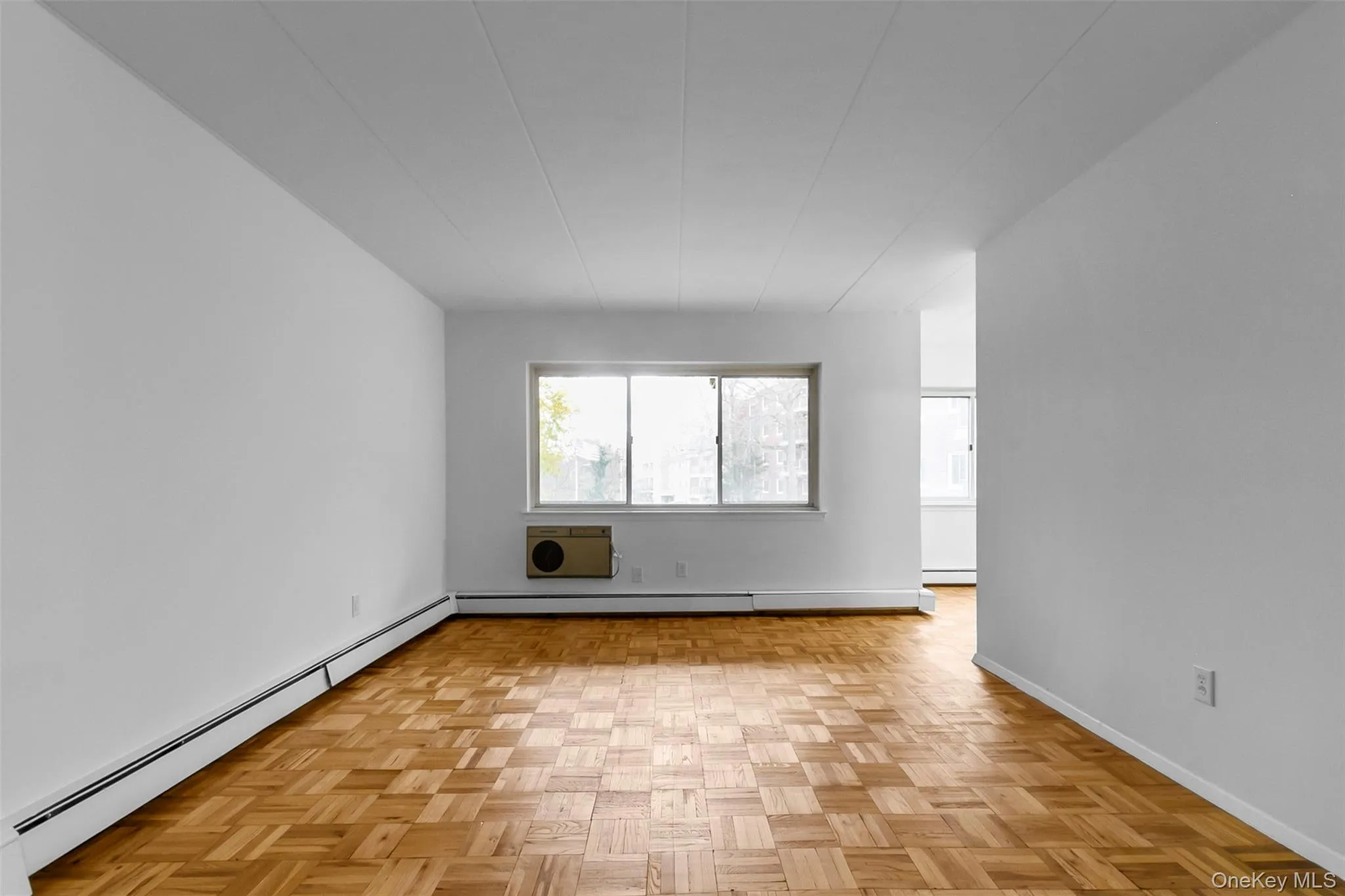 Empty room with a baseboard heating unit and a wall unit AC Empty room with a baseboard heating unit and a wall unit AC