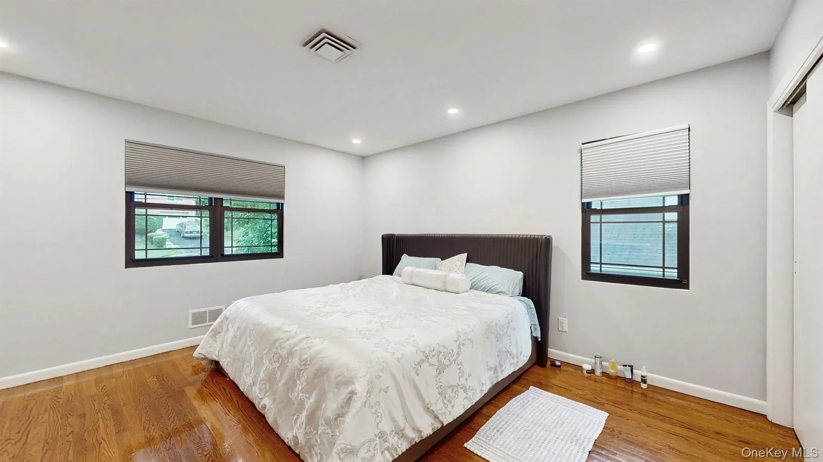 Bedroom with multiple windows, closet, wood finished floors, and recessed lighting. Bedroom with multiple windows, closet, wood finished floors, and recessed lighting.