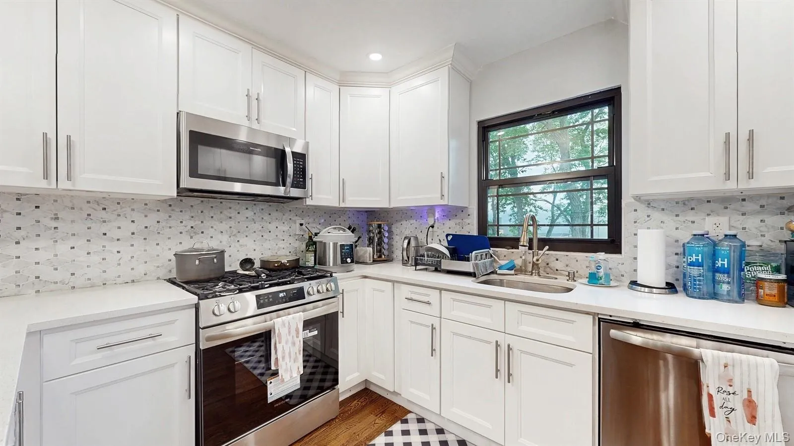 Kitchen featuring stainless steel appliances, light countertops, white cabinetry, Quartz Countertops, backsplash, and recessed lighting Kitchen featuring stainless steel appliances, light countertops, white cabinetry, Quartz Countertops, backsplash, and recessed lighting