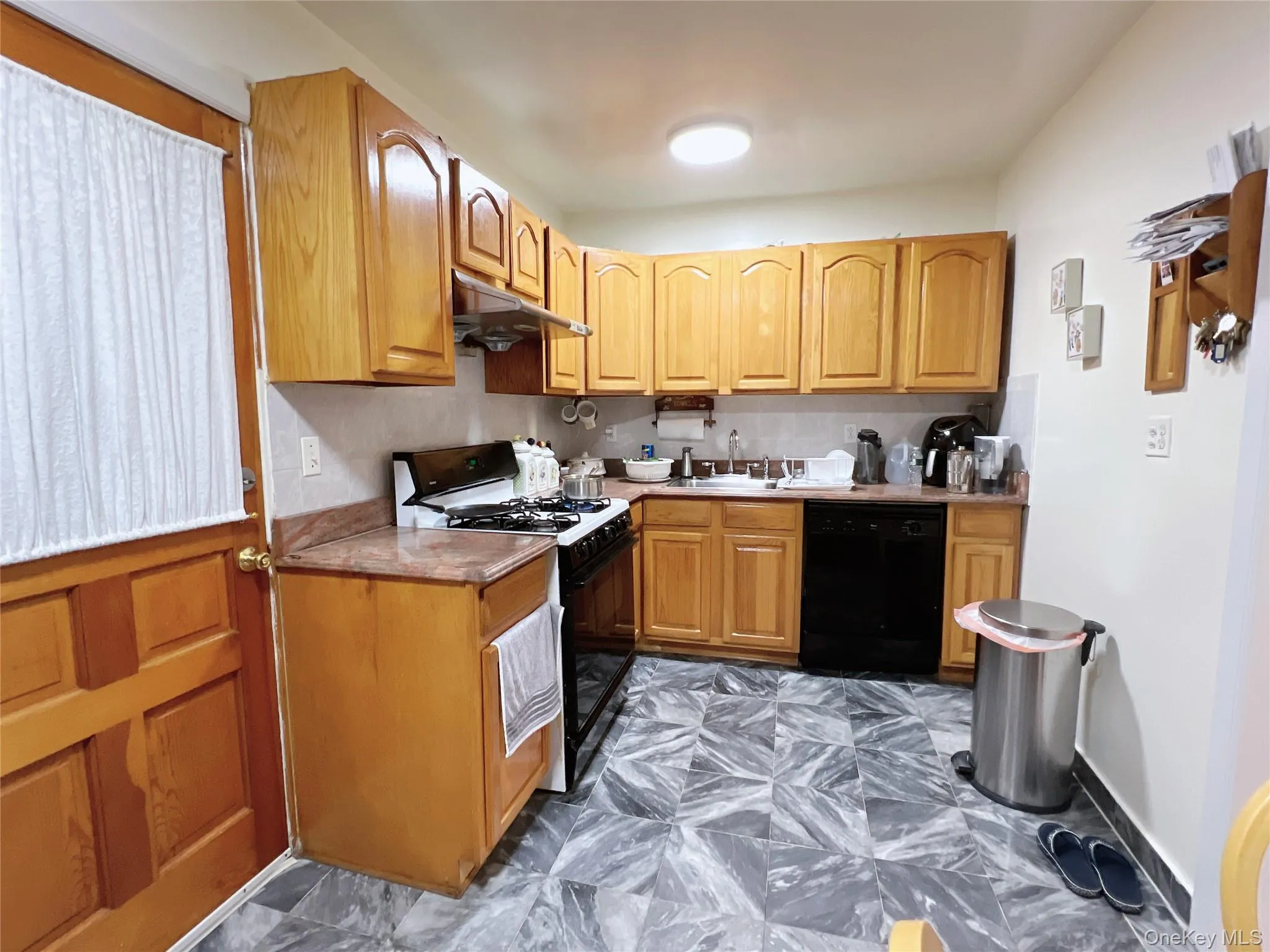 Kitchen featuring black appliances, under cabinet range hood, and brown cabinetry Kitchen featuring black appliances, under cabinet range hood, and brown cabinetry