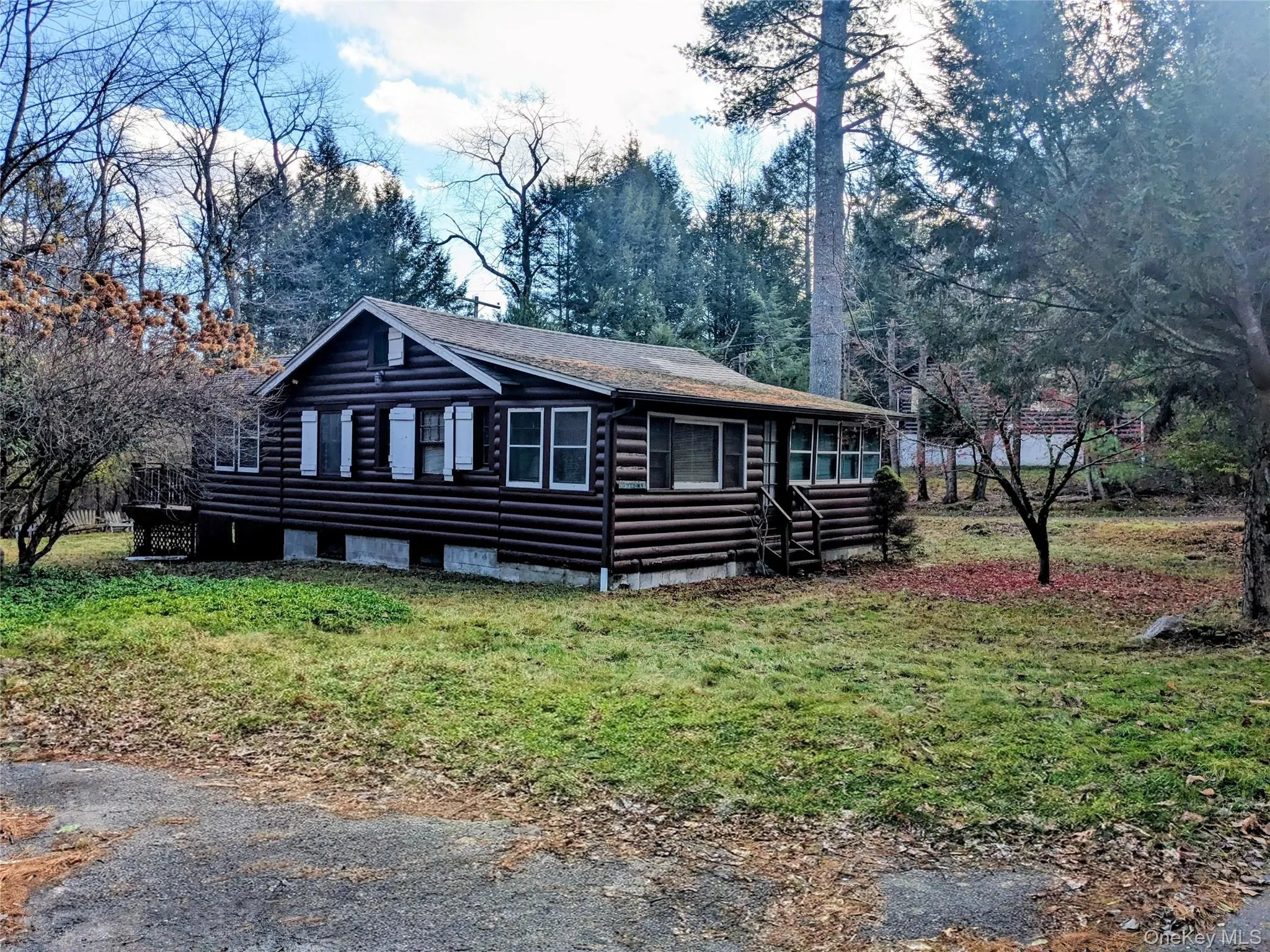 Log home featuring log siding, a front lawn, and view of scattered trees Log home featuring log siding, a front lawn, and view of scattered trees