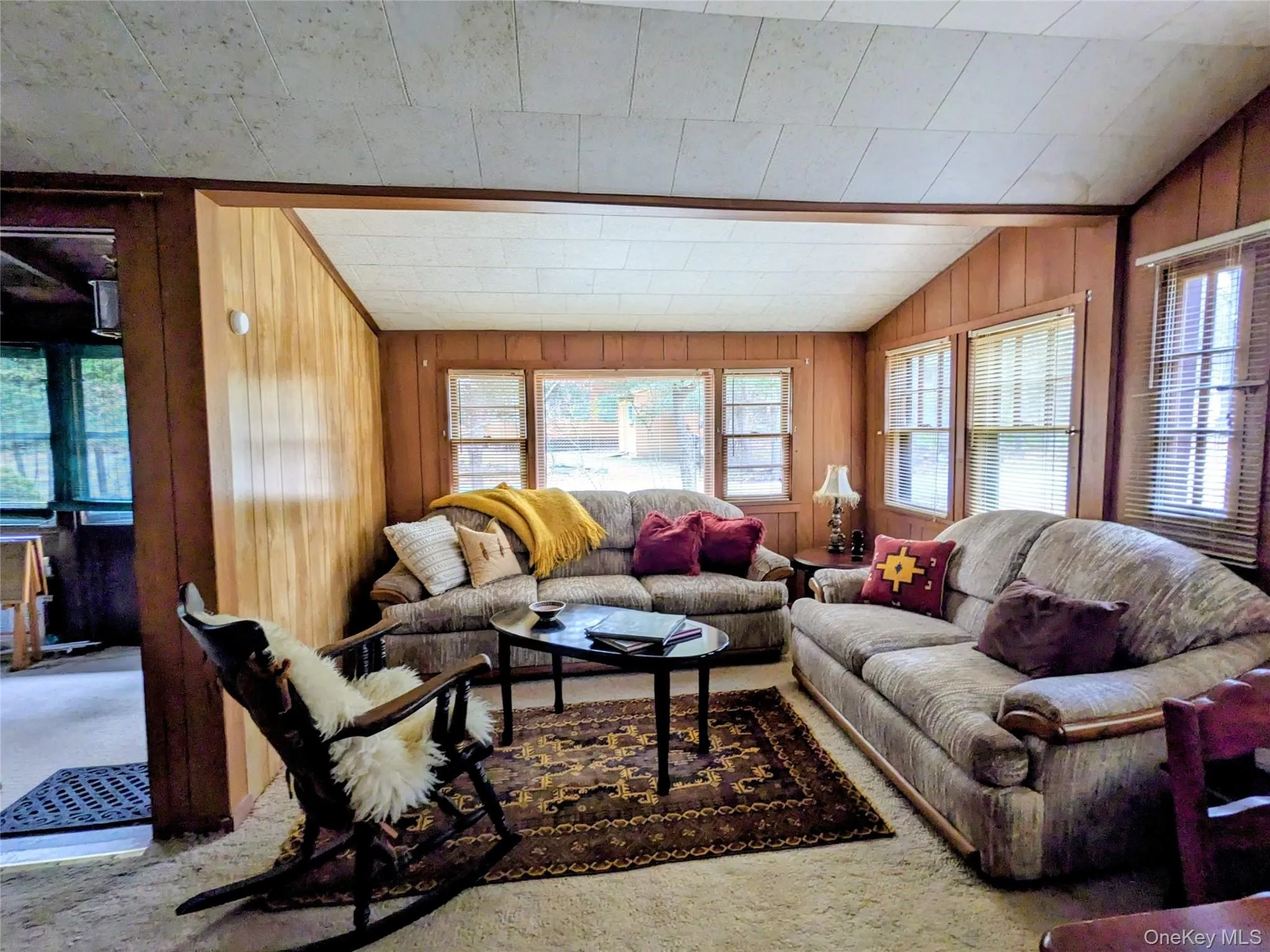 Living area with plenty of natural light, wood walls, vaulted ceiling Living area with plenty of natural light, wood walls, vaulted ceiling