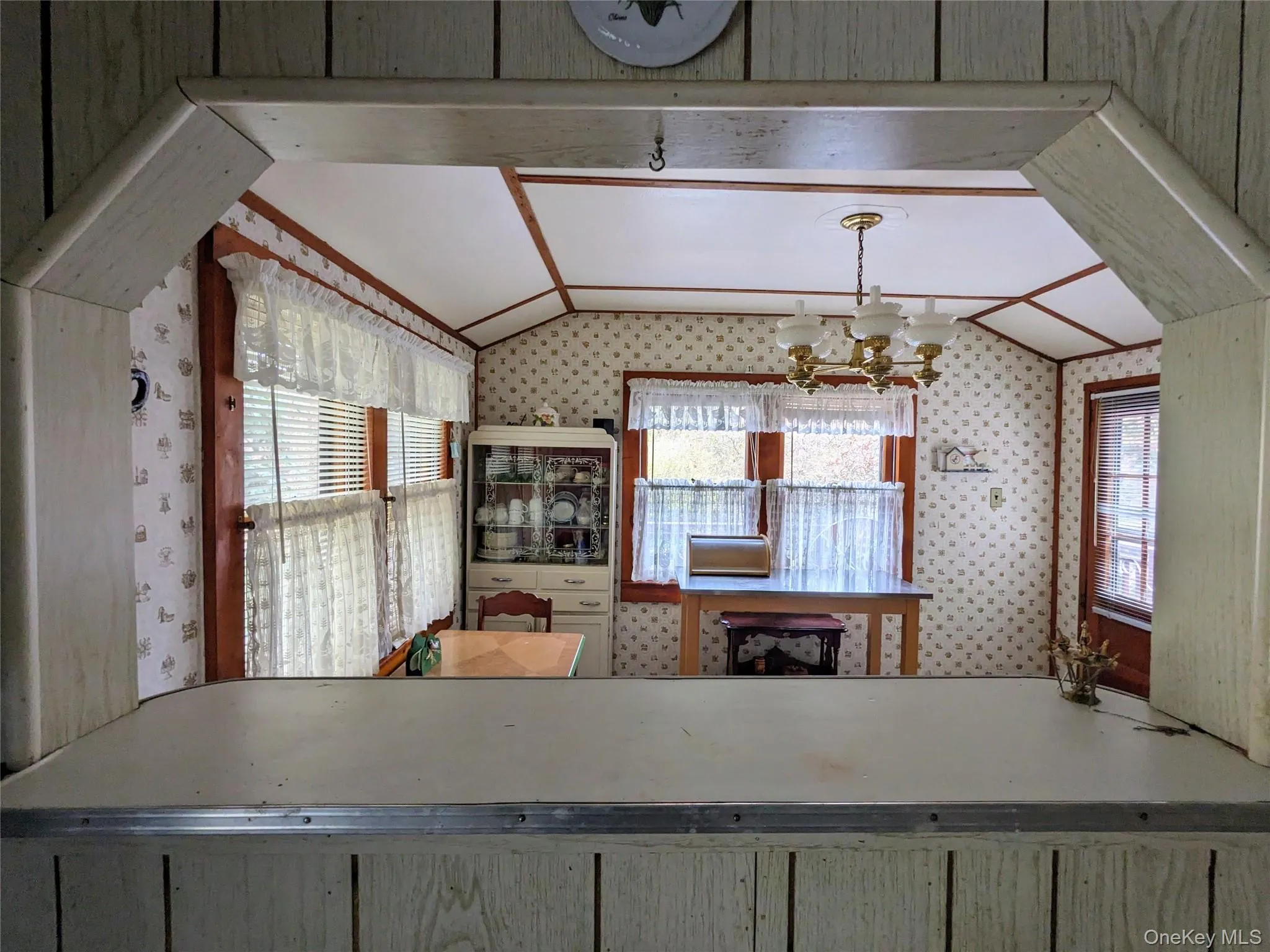 Kitchen with vaulted ceiling, a chandelier, and wallpapered walls Kitchen with vaulted ceiling, a chandelier, and wallpapered walls