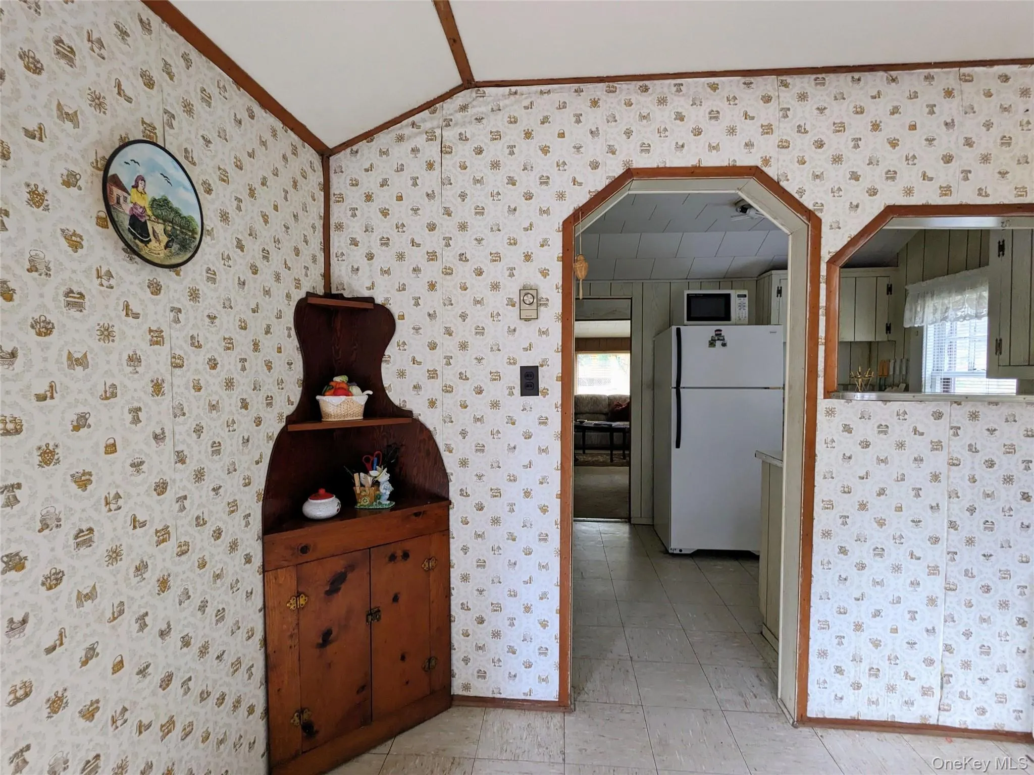 Corridor featuring wallpapered walls, ornamental molding, arched walkways, and vaulted ceiling Corridor featuring wallpapered walls, ornamental molding, arched walkways, and vaulted ceiling