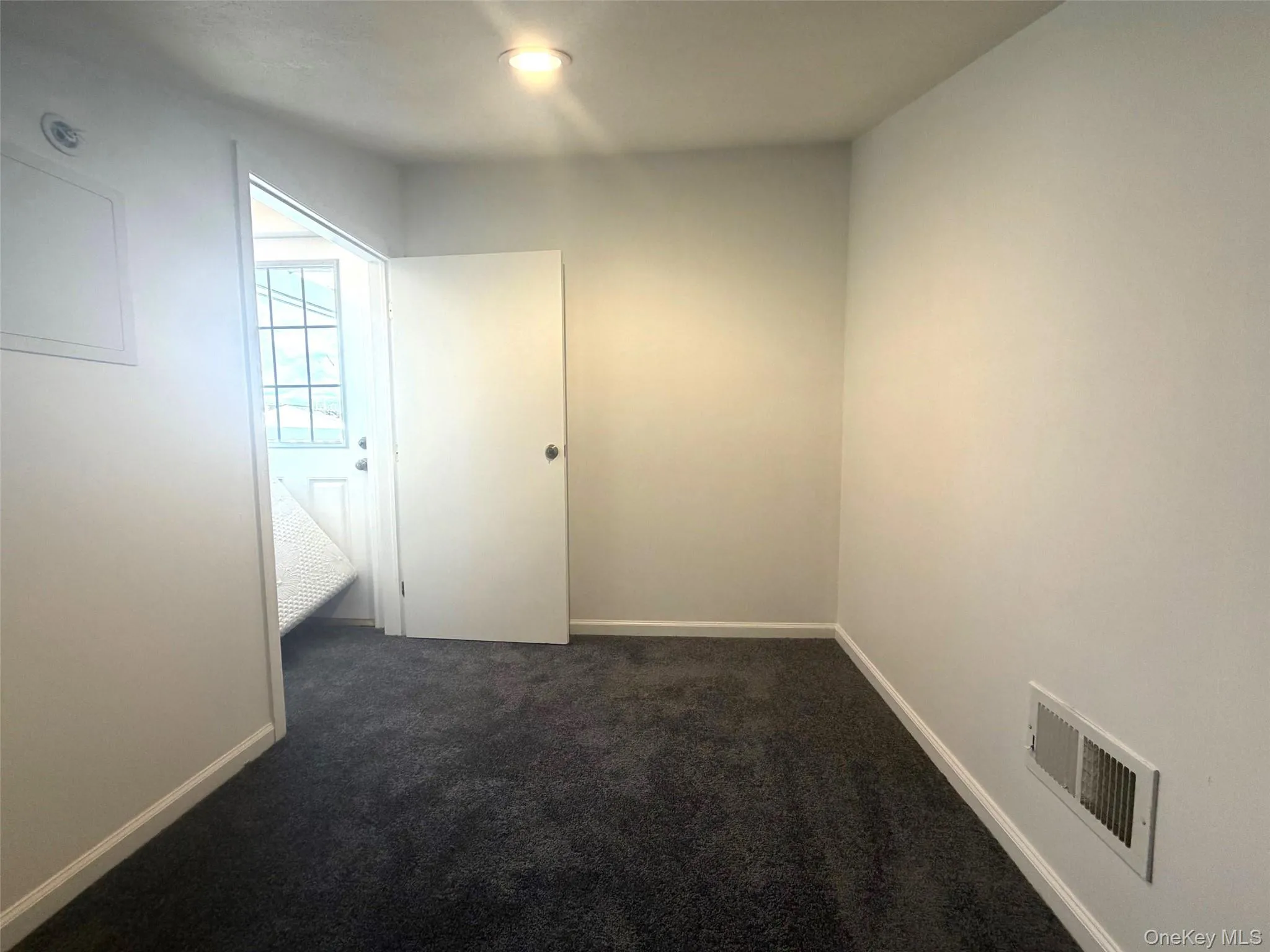 Unfurnished room featuring dark colored carpet and baseboards Unfurnished room featuring dark colored carpet and baseboards