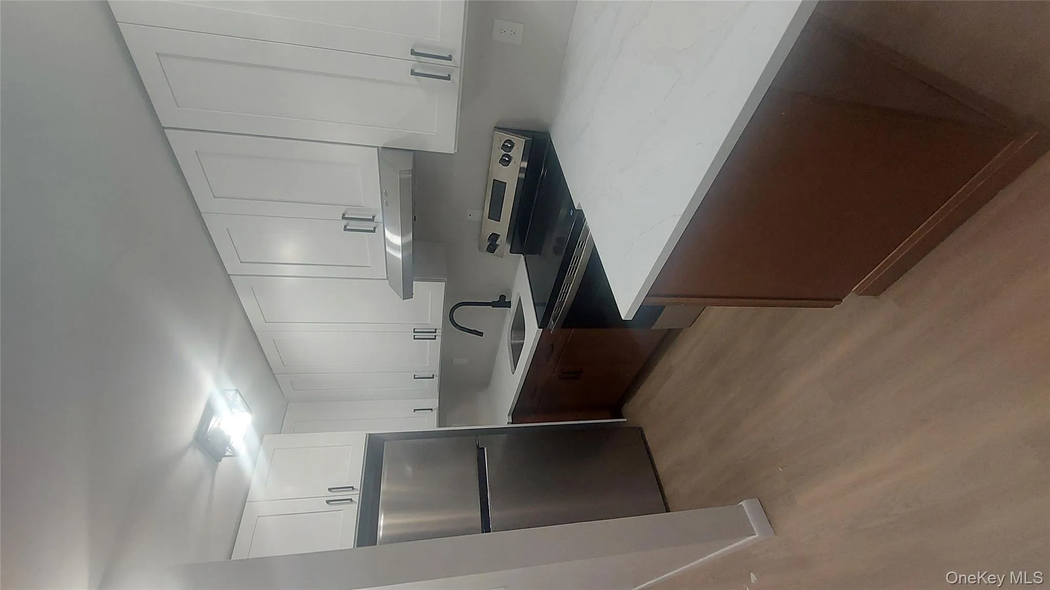 Kitchen with white cabinets, appliances with stainless steel finishes, light wood-style flooring, range hood, and light stone countertops Kitchen with white cabinets, appliances with stainless steel finishes, light wood-style flooring, range hood, and light stone countertops