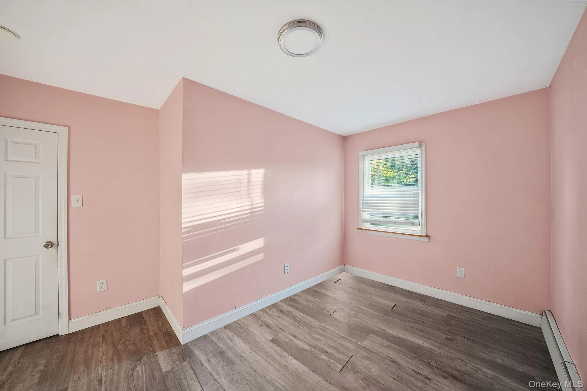 Spare room with baseboard heating, wood finished floors, and lofted ceiling Spare room with baseboard heating, wood finished floors, and lofted ceiling