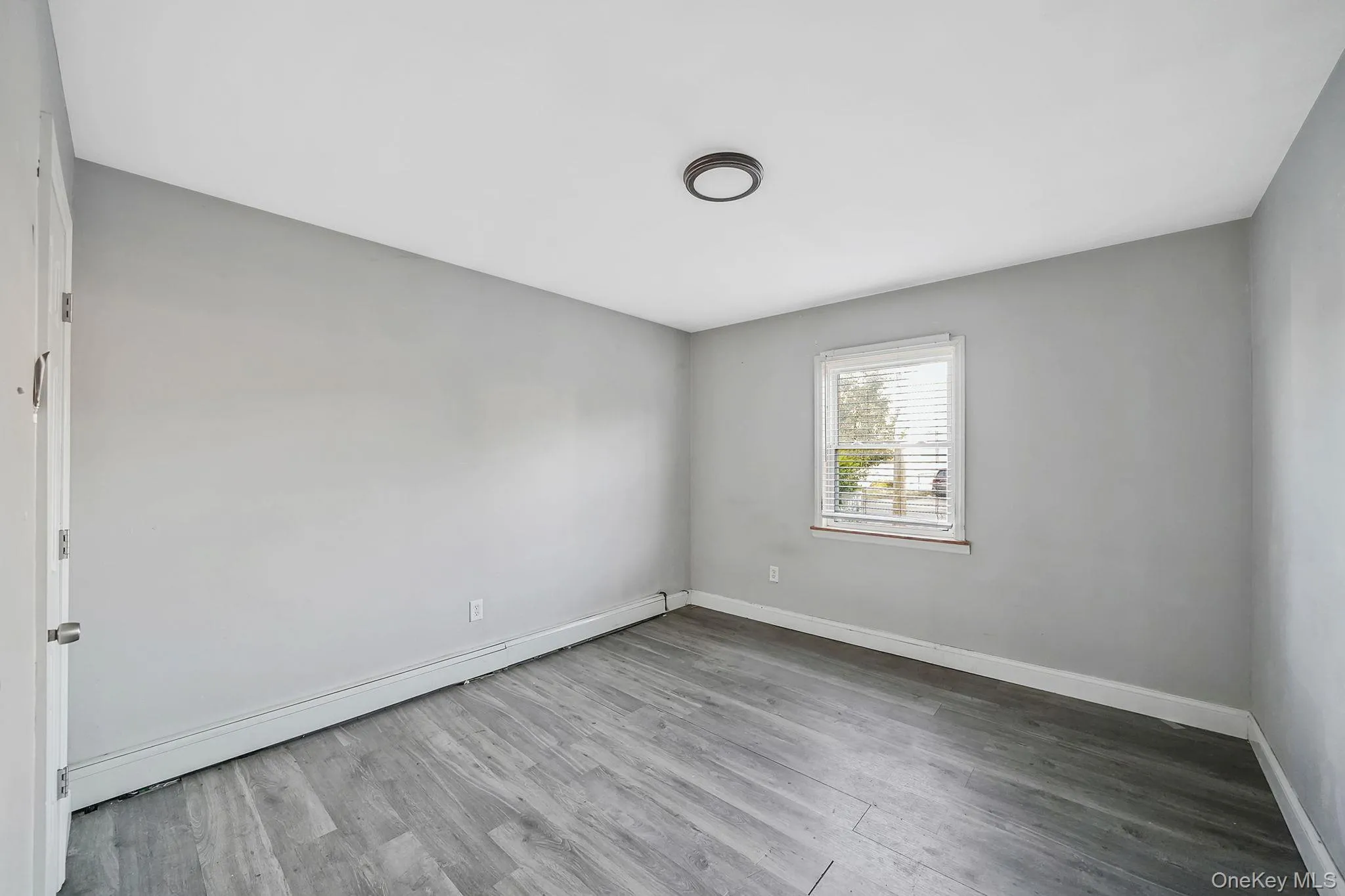 Empty room with a baseboard radiator and wood finished floors Empty room with a baseboard radiator and wood finished floors