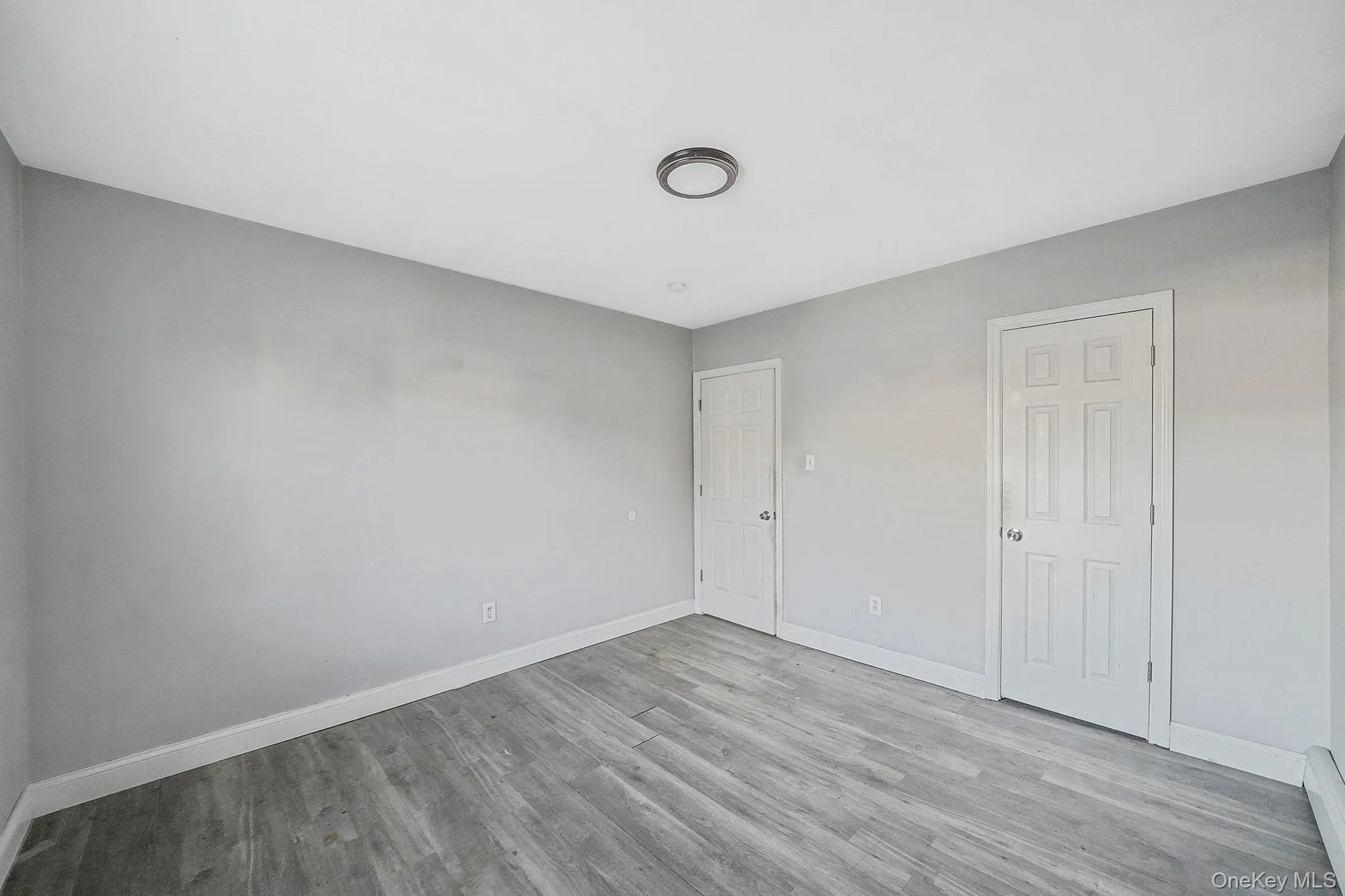 Unfurnished bedroom featuring light wood finished floors and a baseboard heating unit Unfurnished bedroom featuring light wood finished floors and a baseboard heating unit