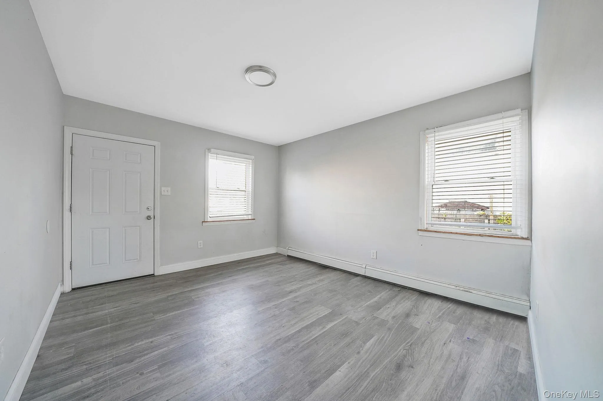 Unfurnished room featuring a baseboard radiator and light wood-style floors Unfurnished room featuring a baseboard radiator and light wood-style floors
