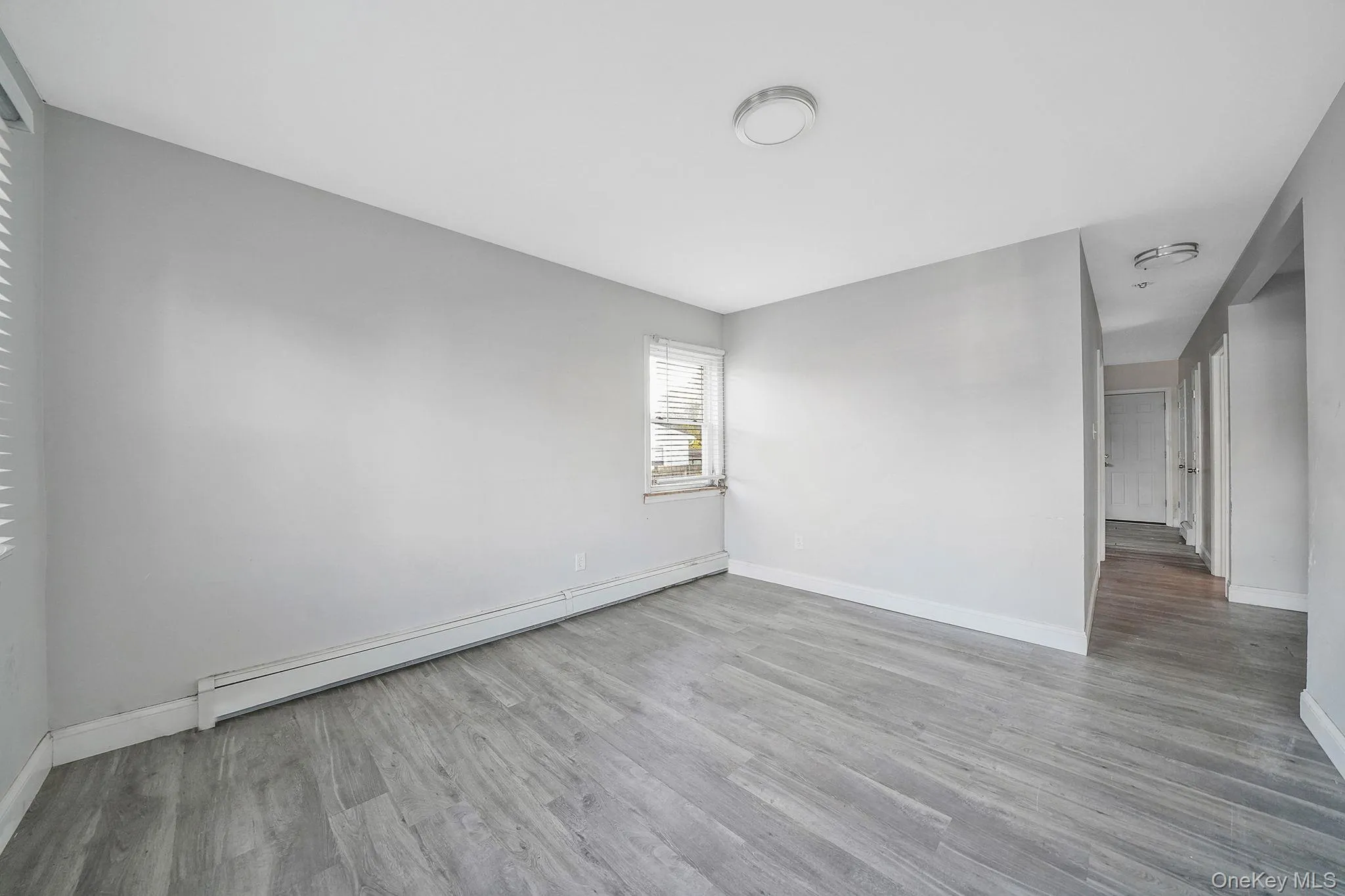 Empty room with baseboard heating and light wood-style flooring Empty room with baseboard heating and light wood-style flooring