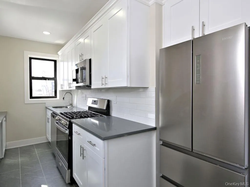 Kitchen featuring appliances with stainless steel finishes, white cabinets, tasteful backsplash, dark countertops, and recessed lighting Kitchen featuring appliances with stainless steel finishes, white cabinets, tasteful backsplash, dark countertops, and recessed lighting