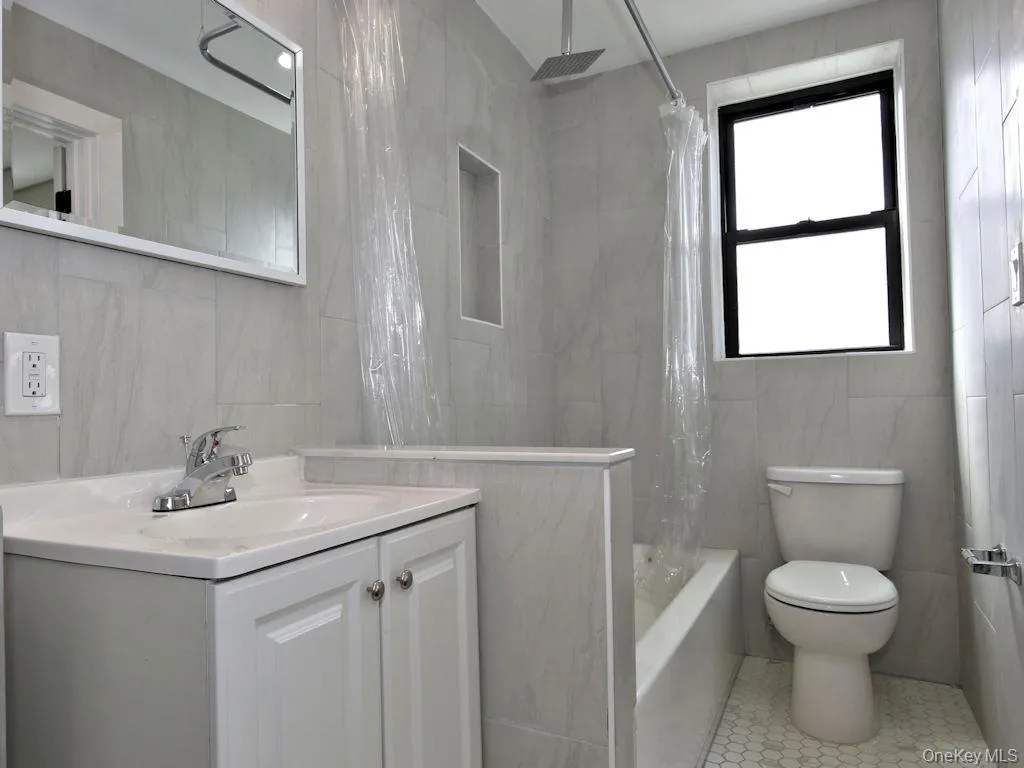 Bathroom featuring tile walls, vanity, a combined bath / shower with rainfall shower, and tile patterned floors Bathroom featuring tile walls, vanity, a combined bath / shower with rainfall shower, and tile patterned floors