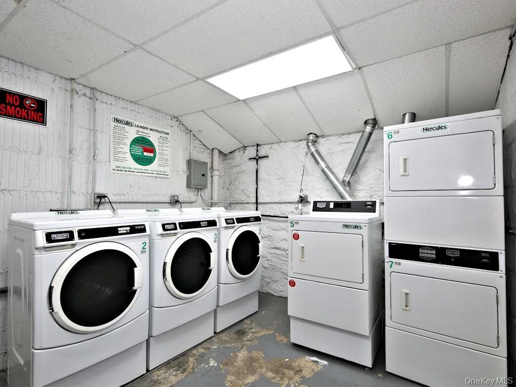 Communal laundry room with a drop ceiling, washing machine and dryer, and electric panel Communal laundry room with a drop ceiling, washing machine and dryer, and electric panel