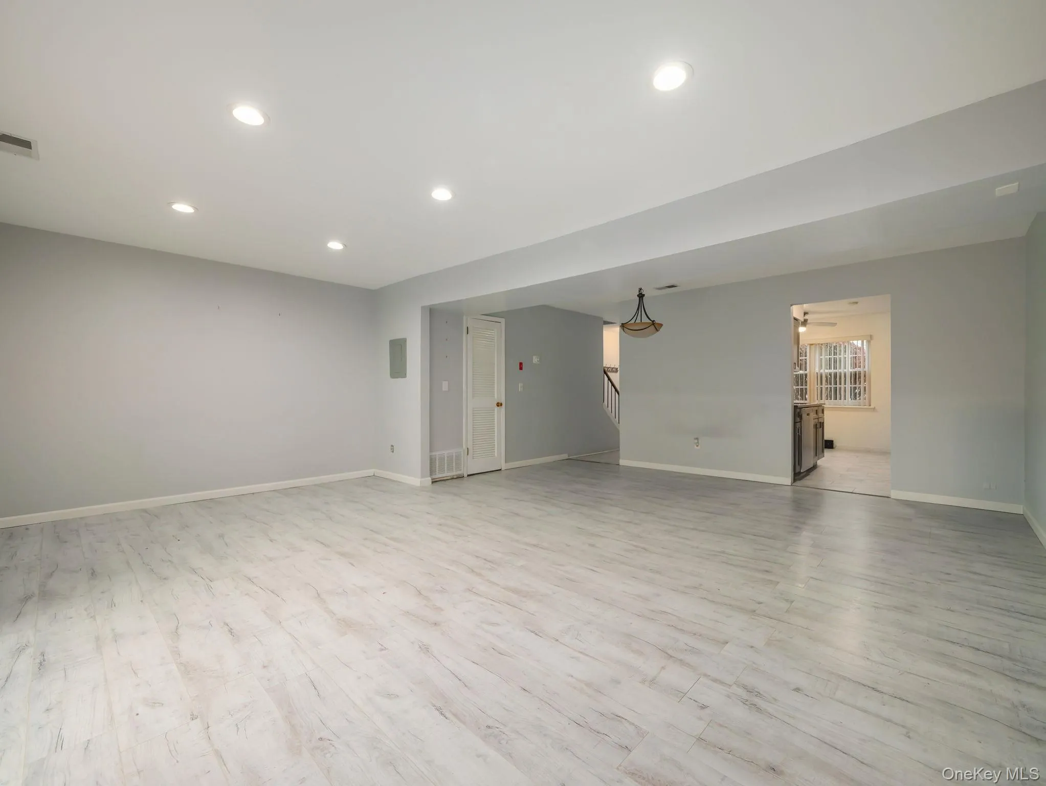 Empty room featuring light wood finished floors, recessed lighting, and stairway Empty room featuring light wood finished floors, recessed lighting, and stairway
