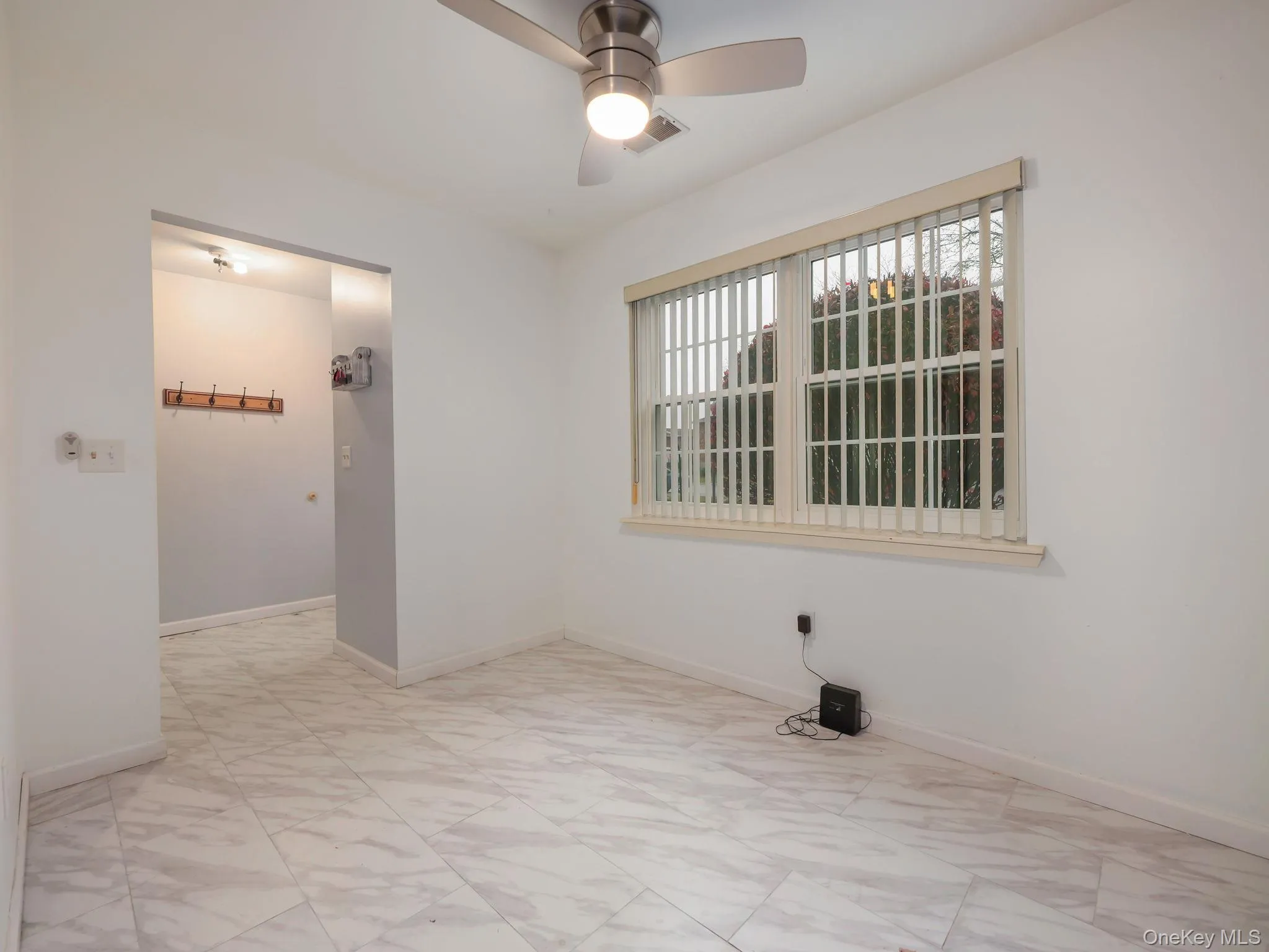 Empty room with a ceiling fan and light marble finish flooring Empty room with a ceiling fan and light marble finish flooring