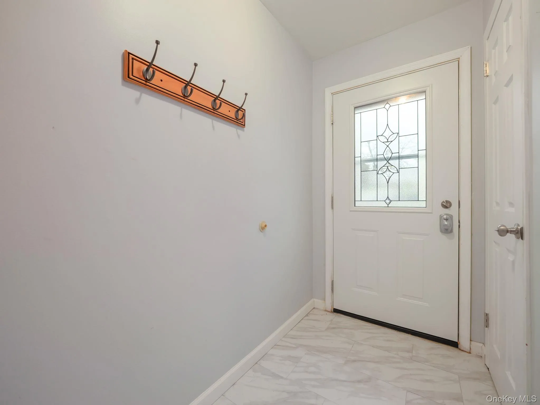 Doorway featuring marble look tiles and baseboards Doorway featuring marble look tiles and baseboards