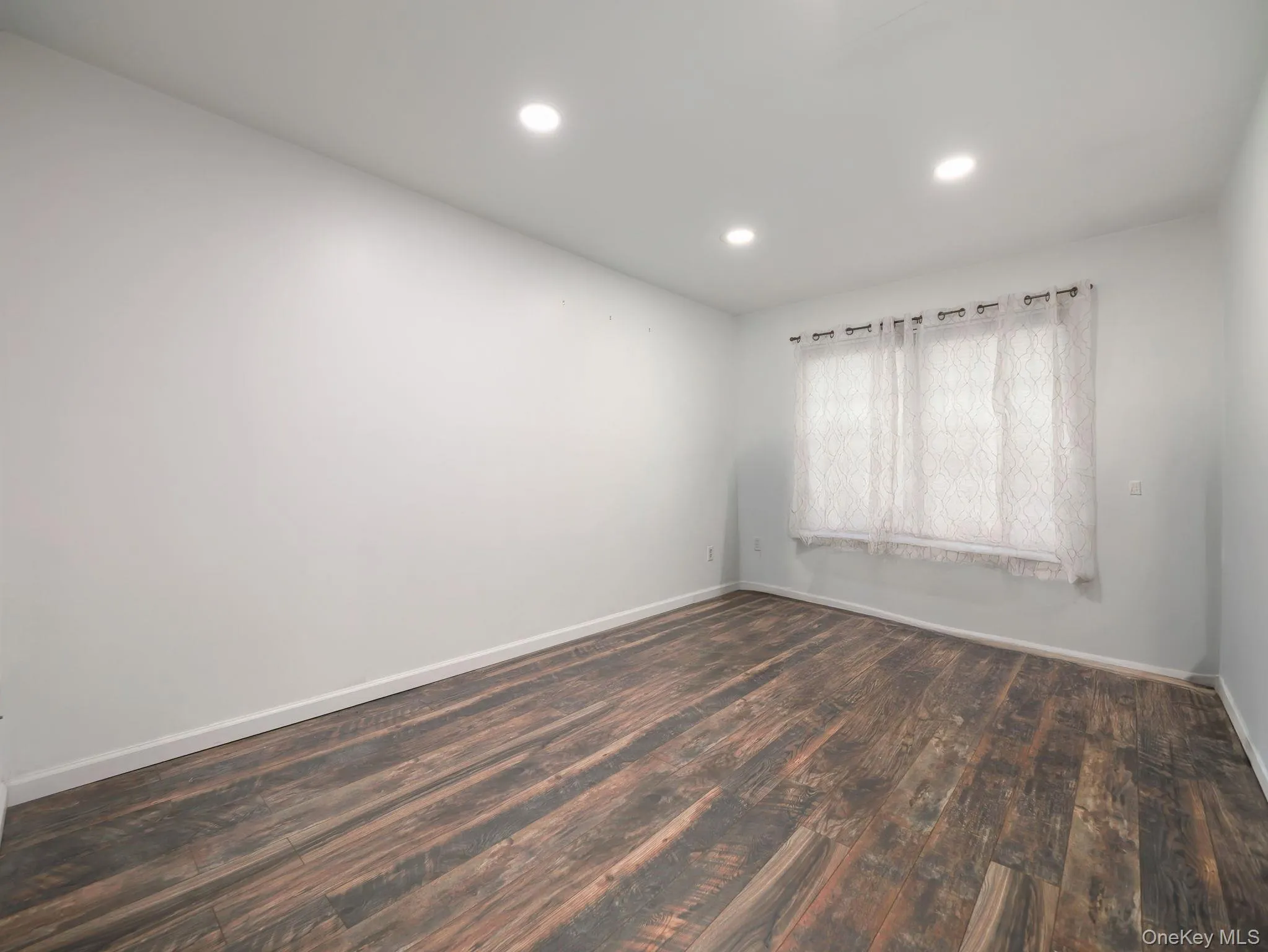 Empty room with dark wood-style flooring and recessed lighting Empty room with dark wood-style flooring and recessed lighting