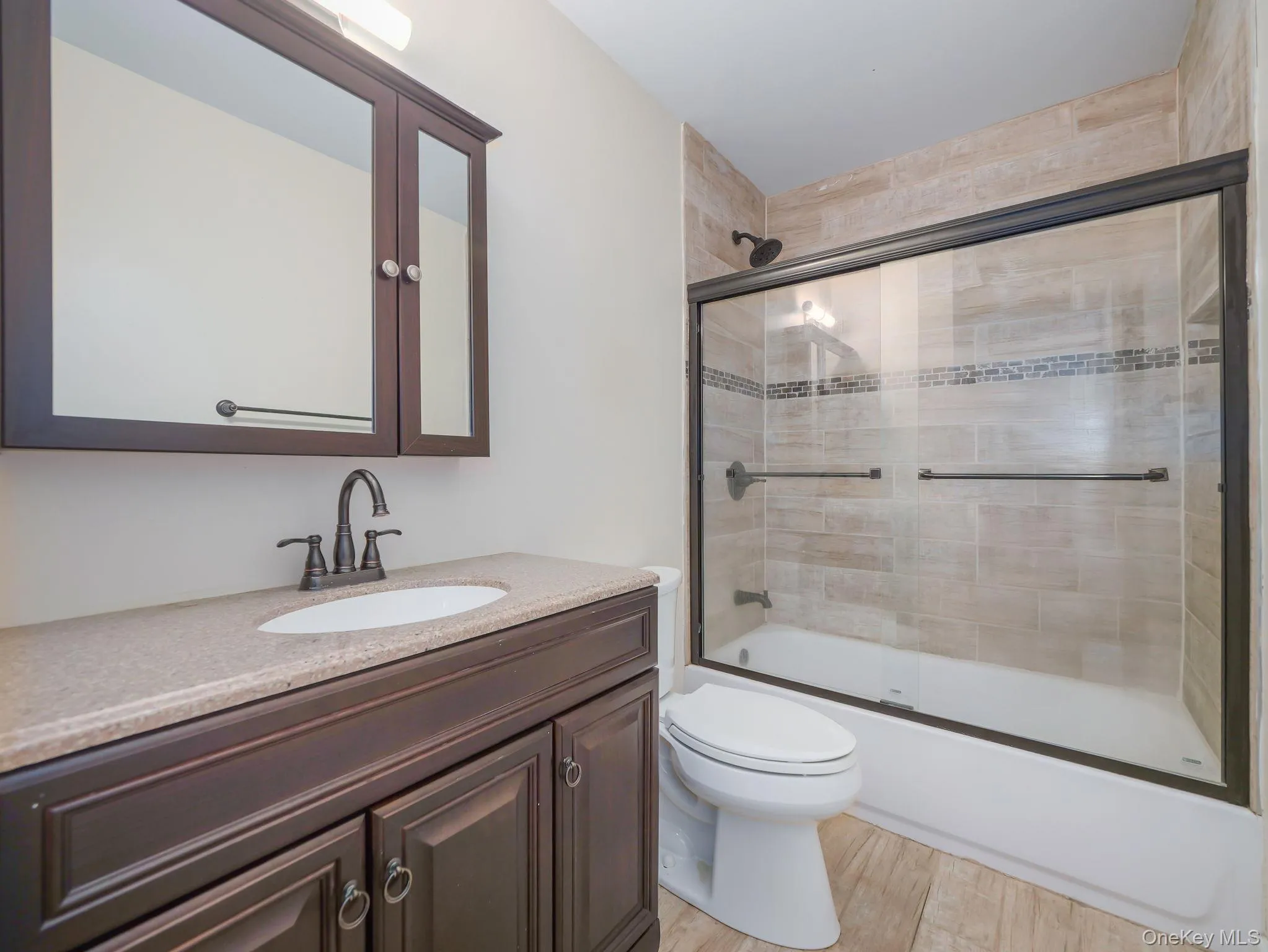 Bathroom featuring shower / bath combination with glass door, light wood-style flooring, and vanity Bathroom featuring shower / bath combination with glass door, light wood-style flooring, and vanity