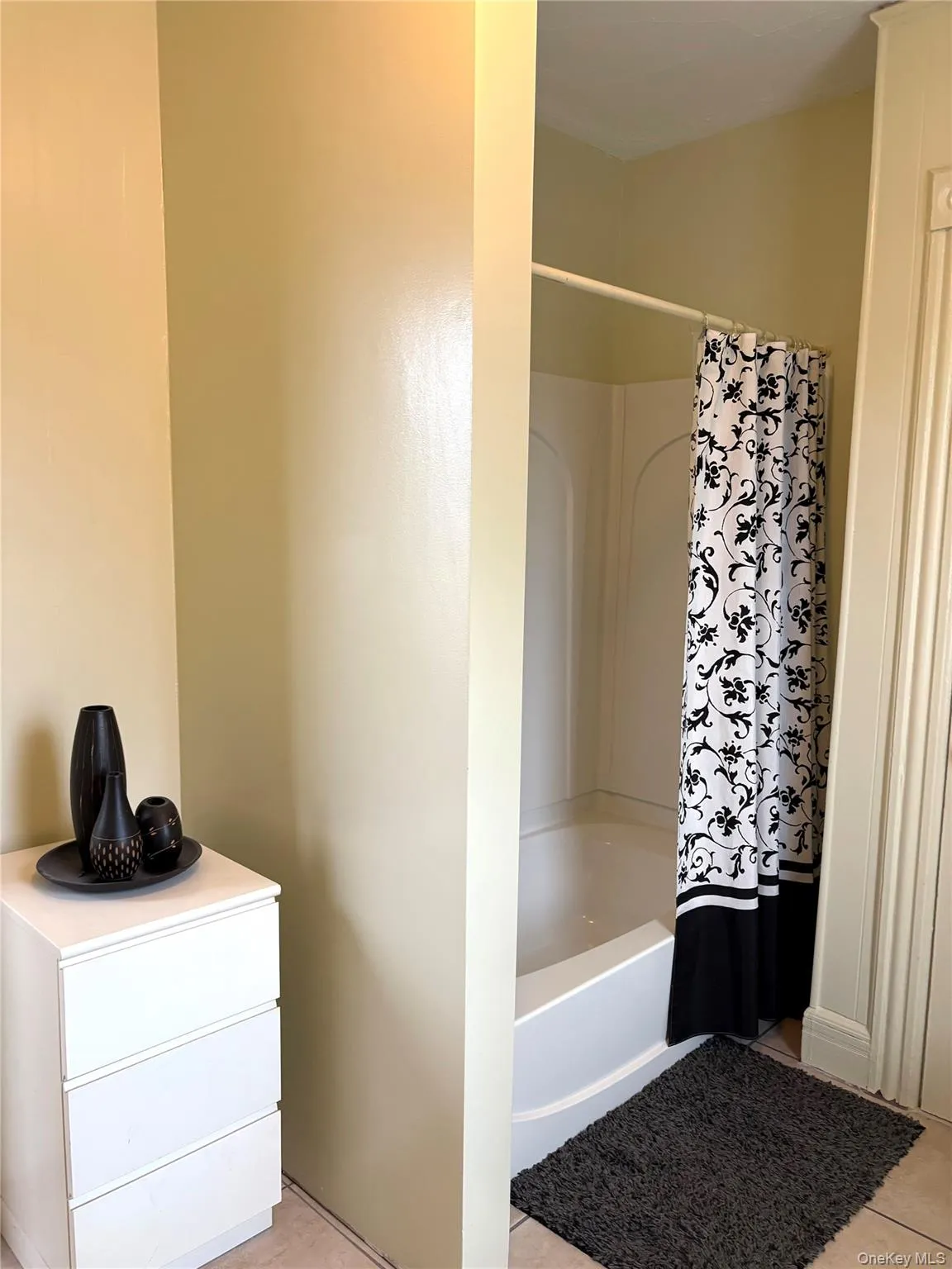 Full bath featuring shower / bathtub combination with curtain and light tile patterned floors Full bath featuring shower / bathtub combination with curtain and light tile patterned floors