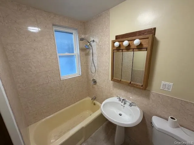 Bathroom with tub / shower combination, tile walls, and wainscoting Bathroom with tub / shower combination, tile walls, and wainscoting