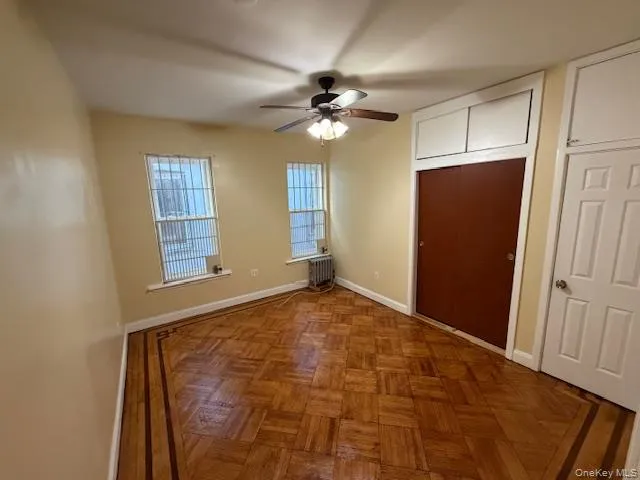 Unfurnished bedroom with 2 closets, a ceiling fan, and radiator heating unit Unfurnished bedroom with 2 closets, a ceiling fan, and radiator heating unit