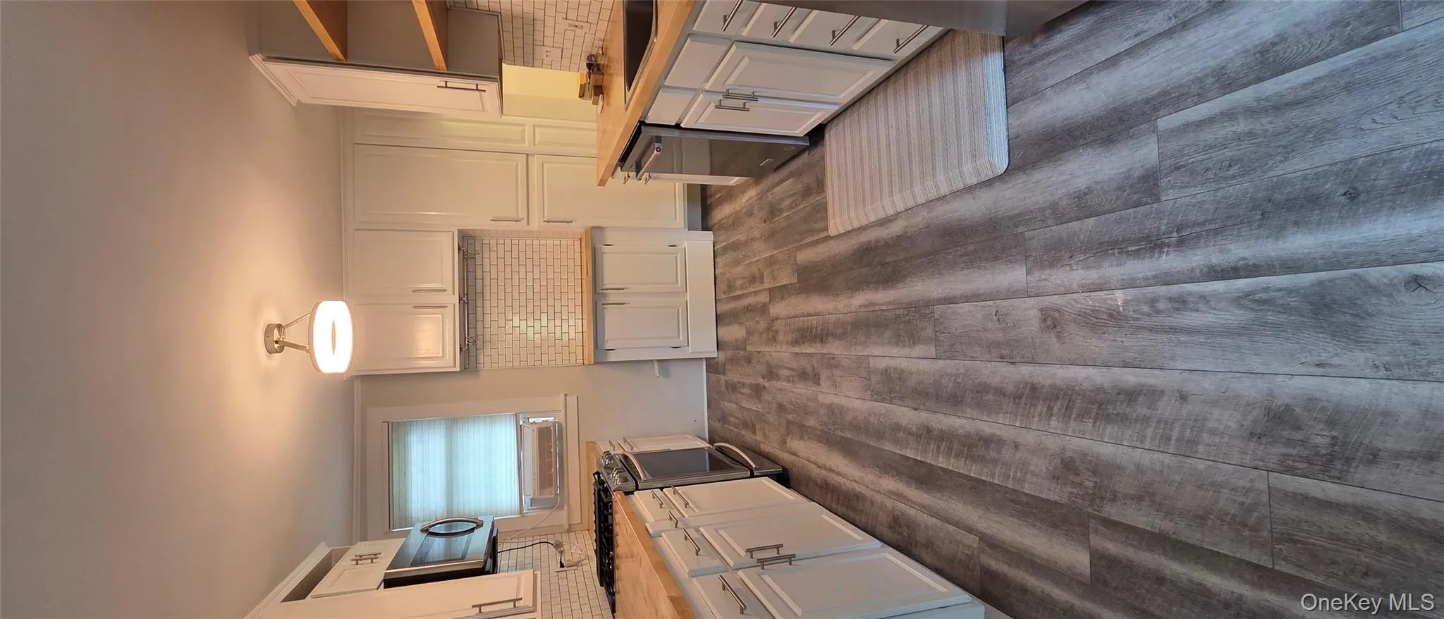Kitchen featuring tasteful backsplash, white cabinetry, and range Kitchen featuring tasteful backsplash, white cabinetry, and range