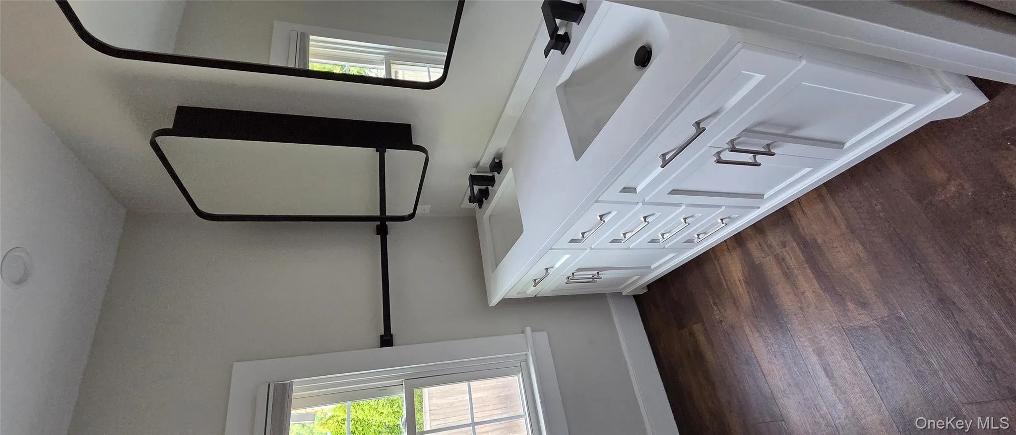 Full bathroom featuring double vanity and dark wood-style floors Full bathroom featuring double vanity and dark wood-style floors