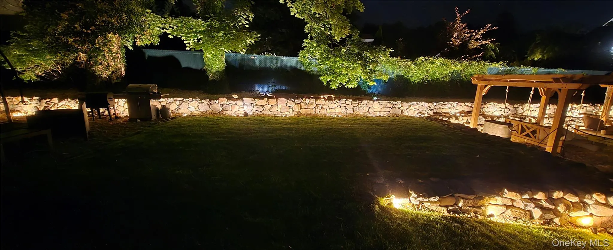 Yard at twilight with a patio area, a lawn, and a pergola Yard at twilight with a patio area, a lawn, and a pergola