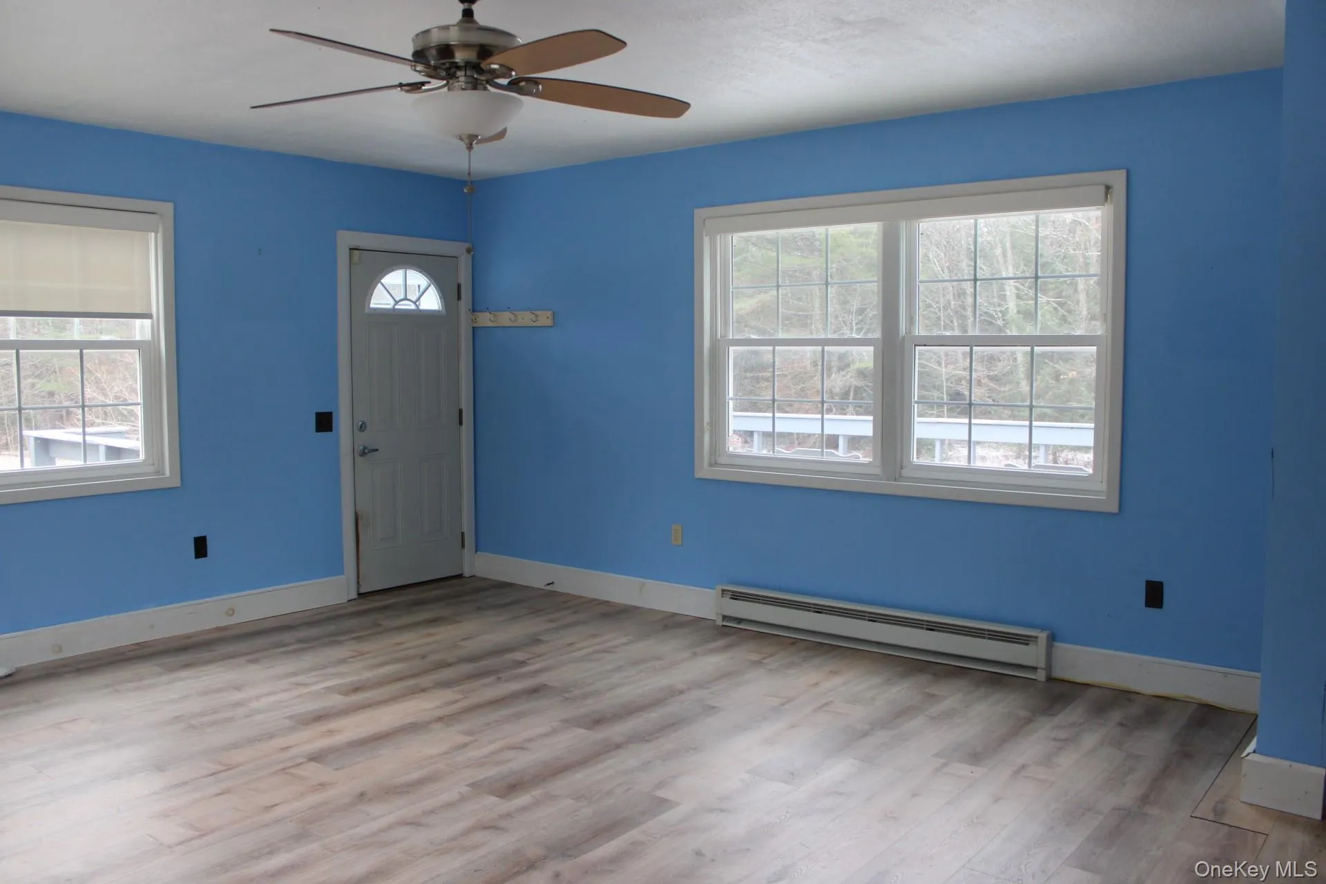 featuring a baseboard heating unit, light wood-style flooring, and a ceiling fan featuring a baseboard heating unit, light wood-style flooring, and a ceiling fan