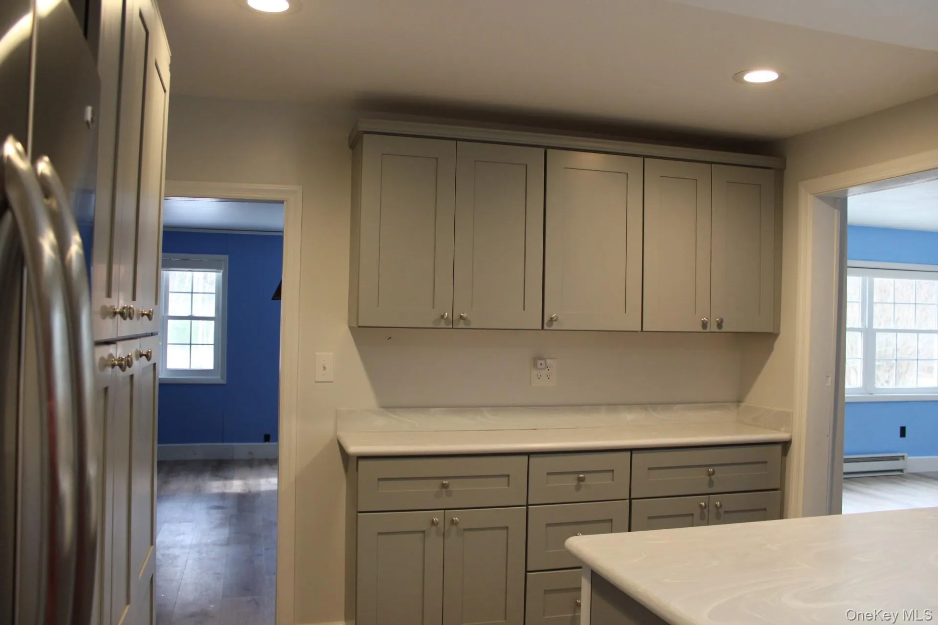 Kitchen featuring gray cabinets, freestanding refrigerator, recessed lighting, wood finished floors, and a baseboard radiator Kitchen featuring gray cabinets, freestanding refrigerator, recessed lighting, wood finished floors, and a baseboard radiator