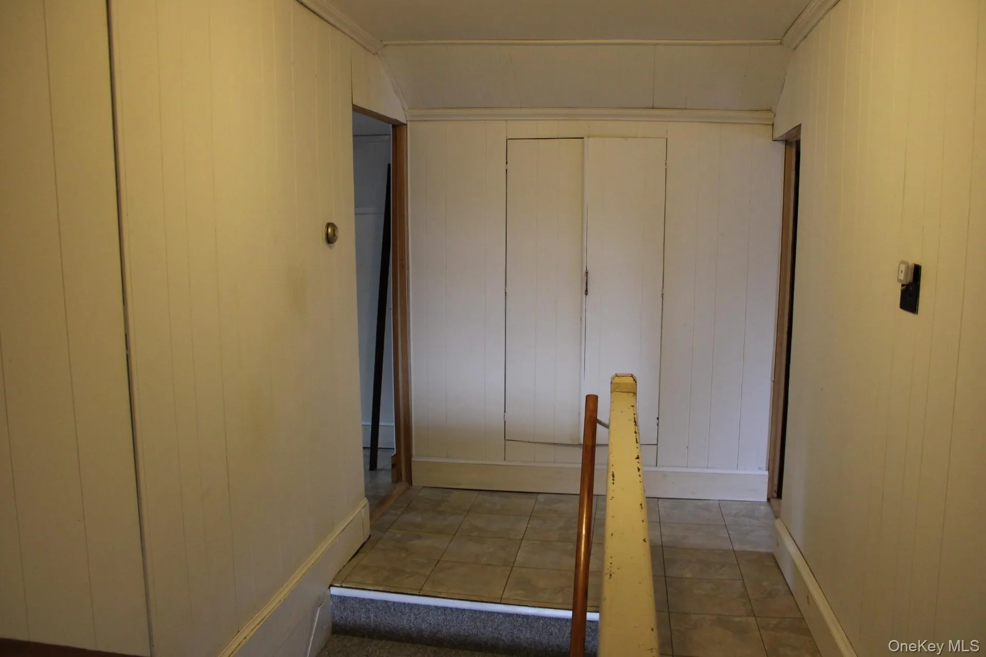 Upstairs hall featuring wood walls and light tile patterned flooring Upstairs hall featuring wood walls and light tile patterned flooring