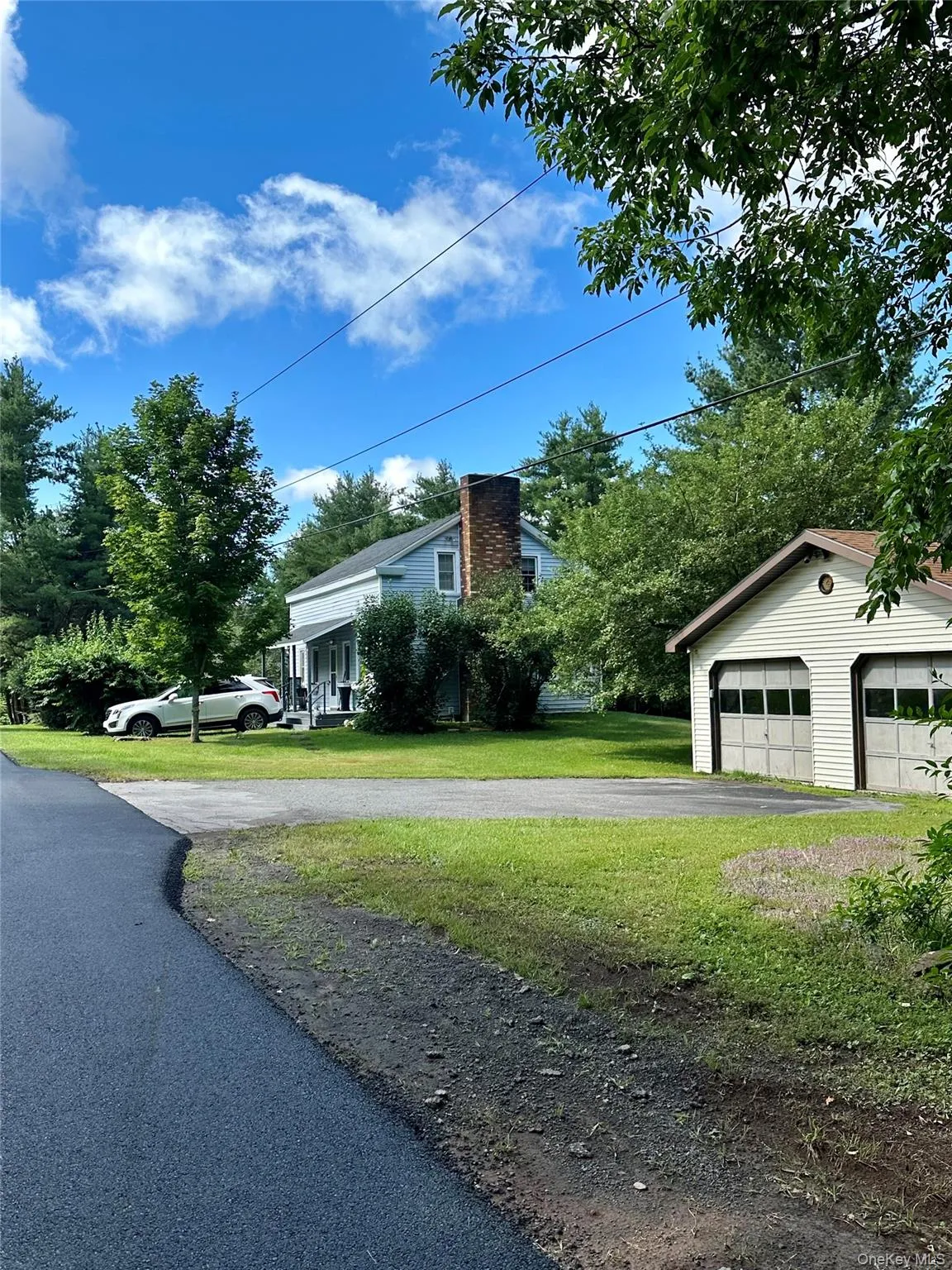 View of front of house featuring an outbuilding, a front yard, a chimney, and a garage View of front of house featuring an outbuilding, a front yard, a chimney, and a garage