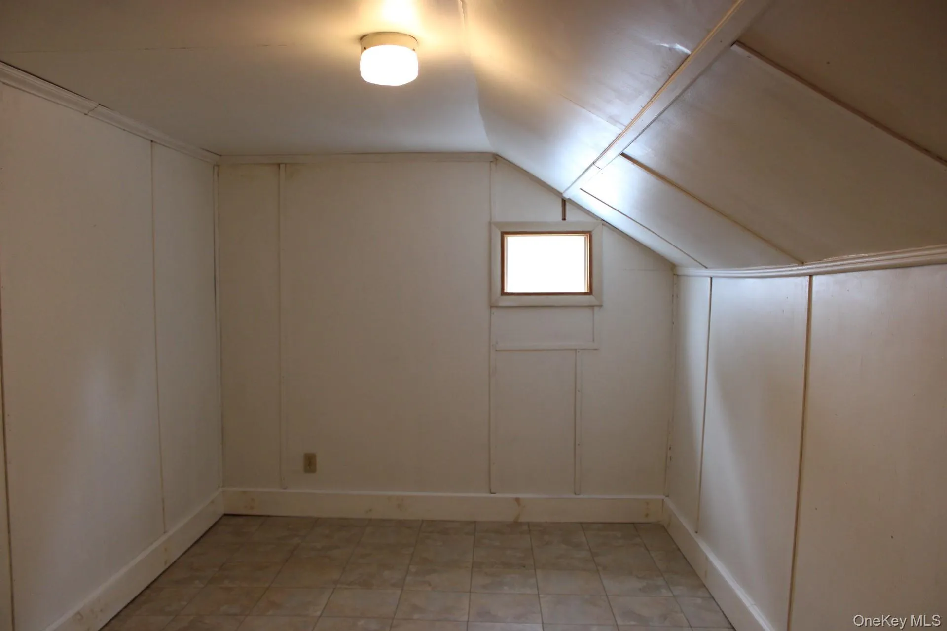 Bonus room with lofted ceiling, a decorative wall, and light tile patterned floors Bonus room with lofted ceiling, a decorative wall, and light tile patterned floors