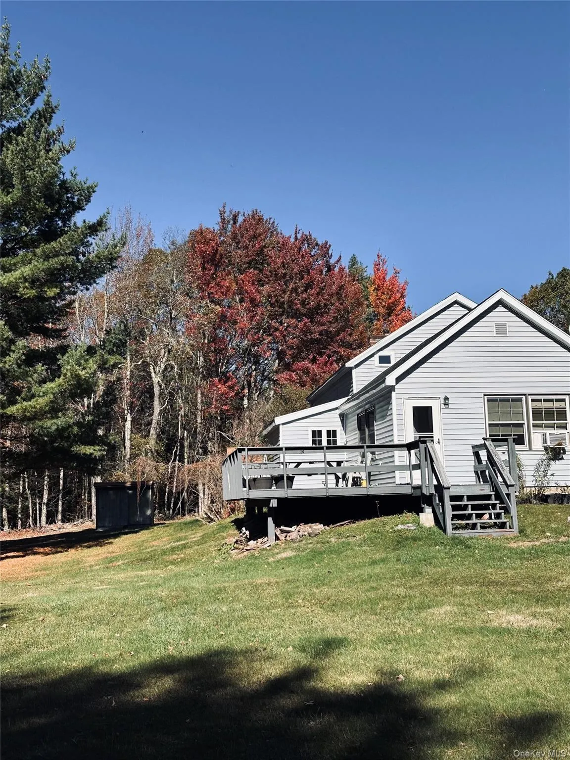 Rear view of property featuring a lawn and a wooden deck Rear view of property featuring a lawn and a wooden deck