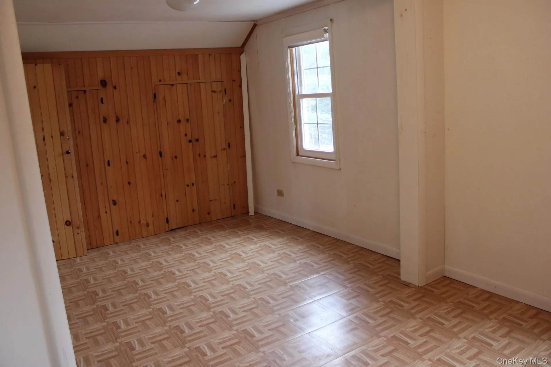 Unfurnished room featuring wooden walls and parquet flooring Unfurnished room featuring wooden walls and parquet flooring