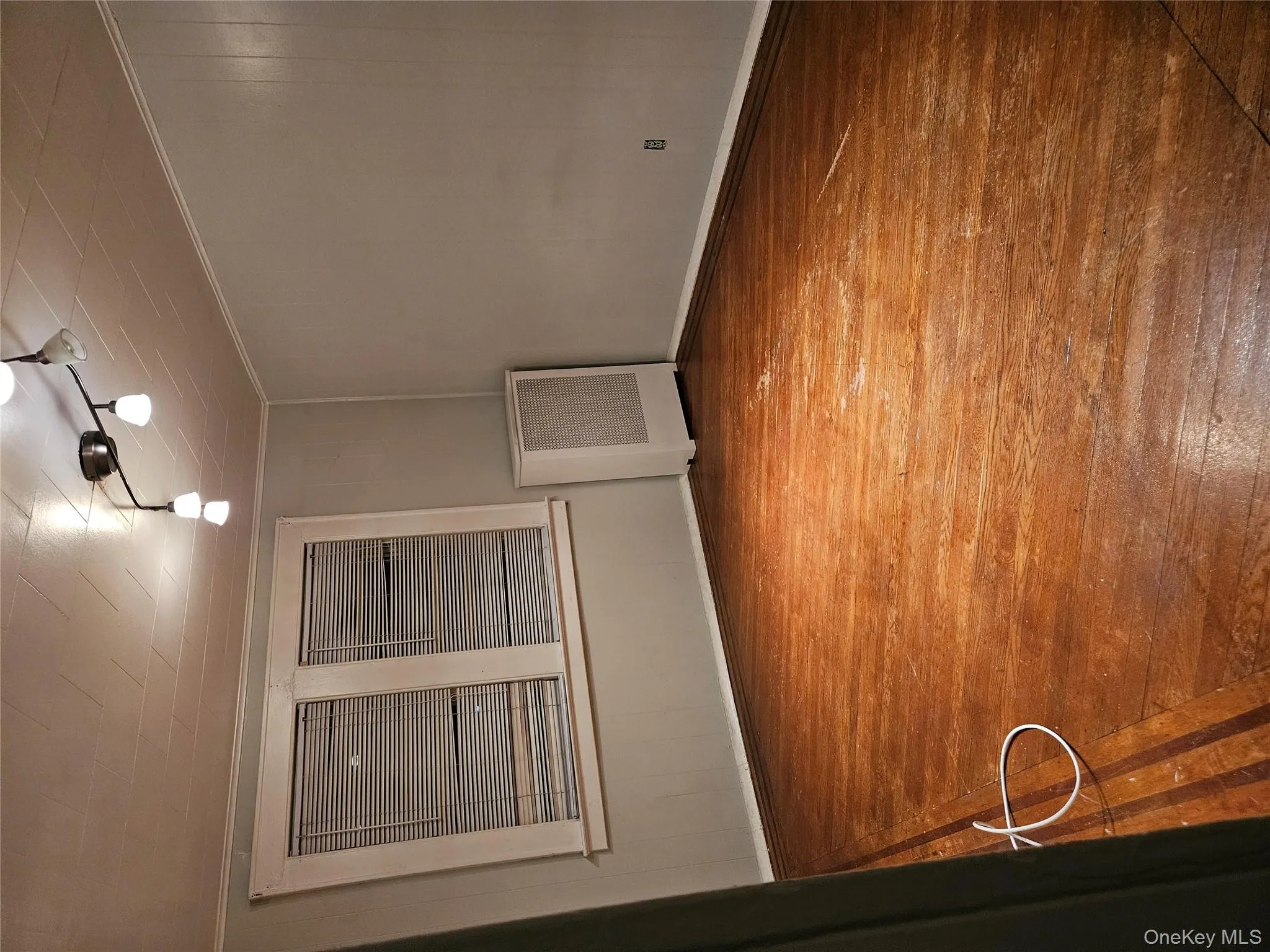 Unfurnished room with wood-type flooring, radiator heating unit, wood walls, and crown molding Unfurnished room with wood-type flooring, radiator heating unit, wood walls, and crown molding