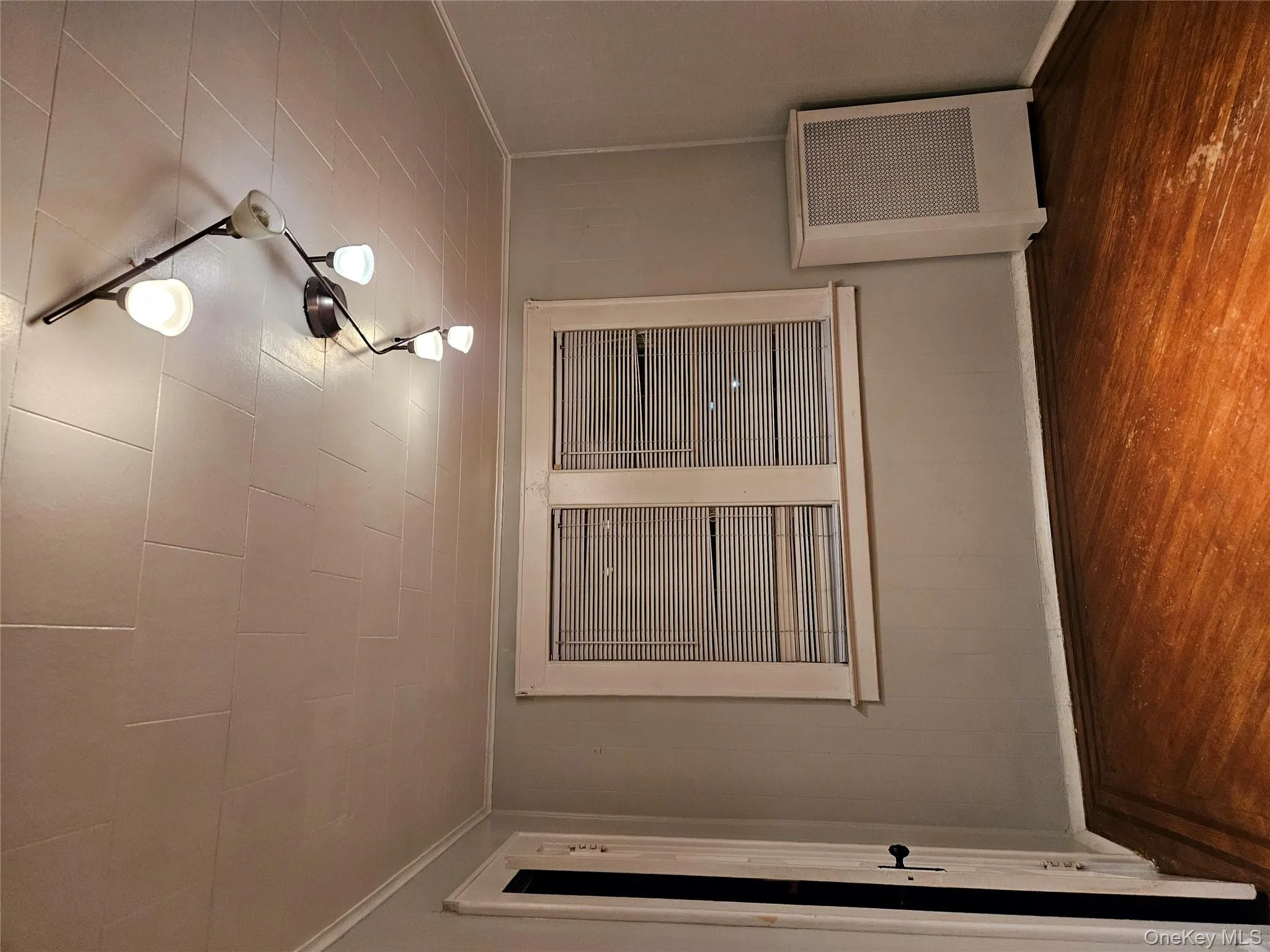 Spare room with dark wood-type flooring, wooden walls, rail lighting, ornamental molding, and radiator Spare room with dark wood-type flooring, wooden walls, rail lighting, ornamental molding, and radiator