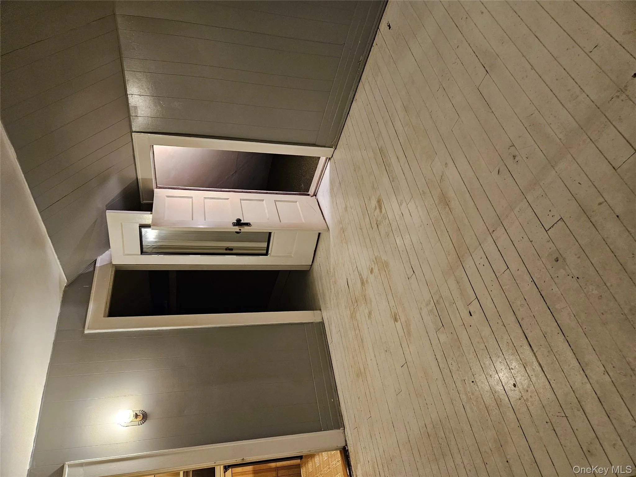 Unfurnished bedroom with light wood-style floors, wooden walls, lofted ceiling, and a spacious closet Unfurnished bedroom with light wood-style floors, wooden walls, lofted ceiling, and a spacious closet